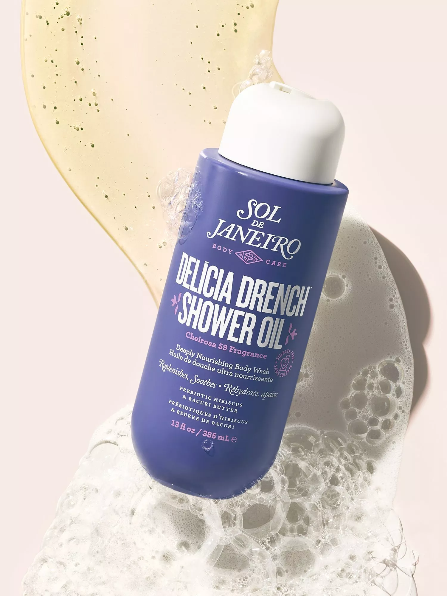 Sol de Janeiro Delicia Drench Shower Oil bottle with bubbles and golden gel swirls on pale background