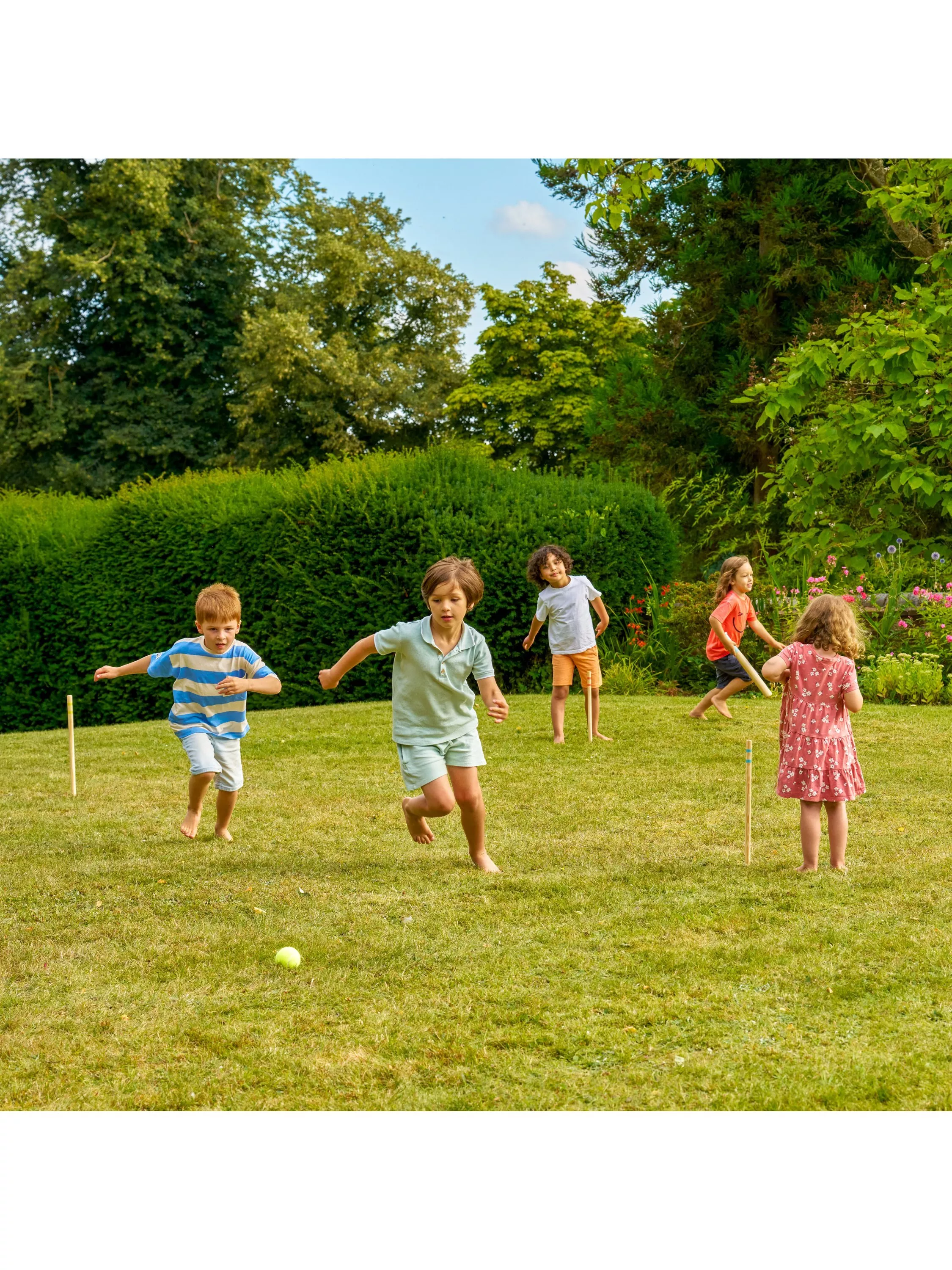 Smiling toddler leaning on wooden garden playhouse balcony with green windows, sunny outdoor backyard scene