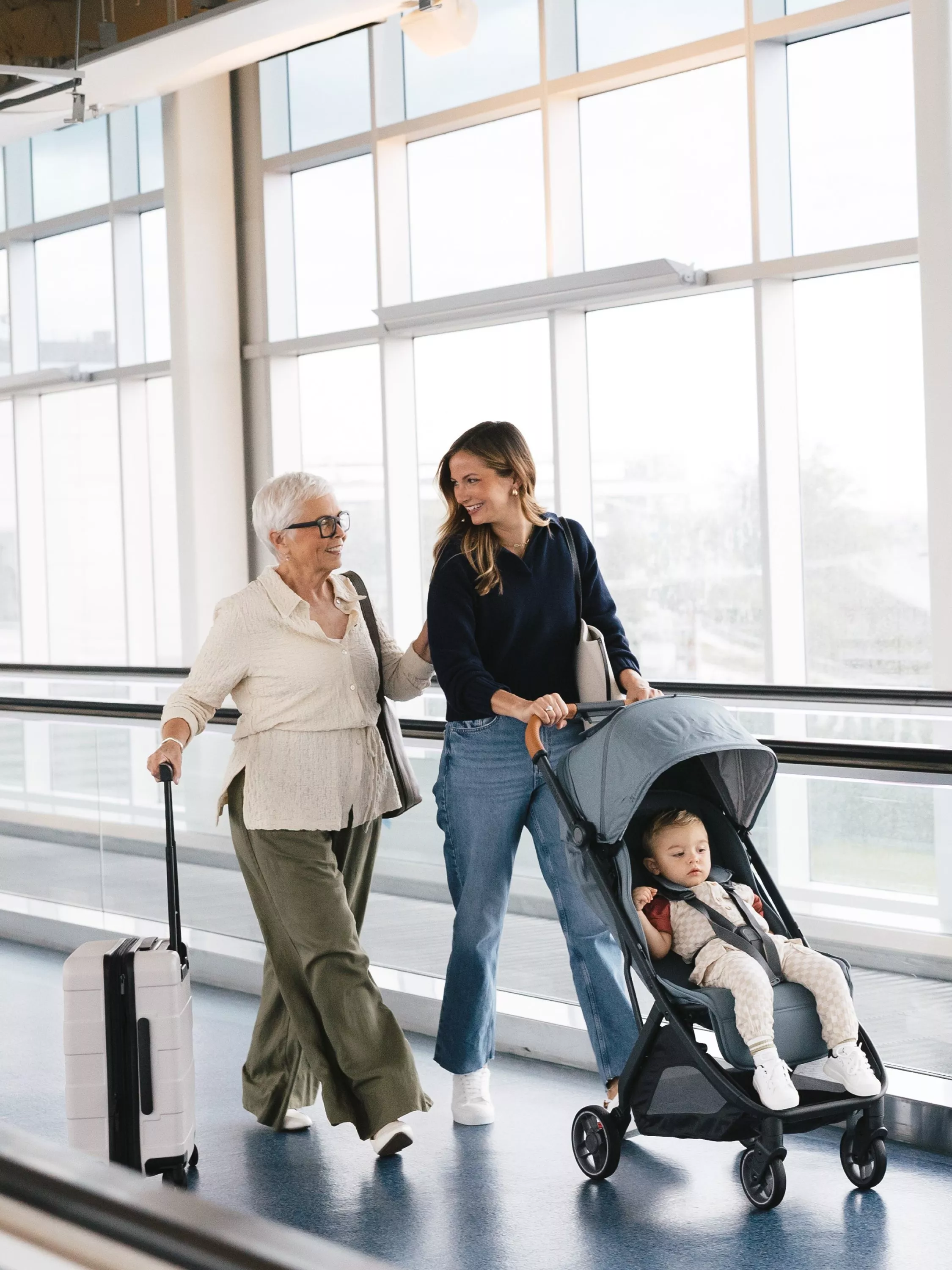 Baby in a pram being pushed by a woman, with another woman walking beside them