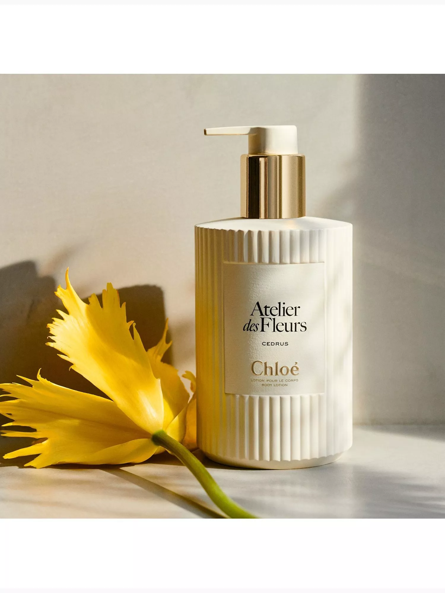 Chloé Atelier des Fleurs Cedrus body lotion pump bottle with yellow flower, luxury skincare product shot