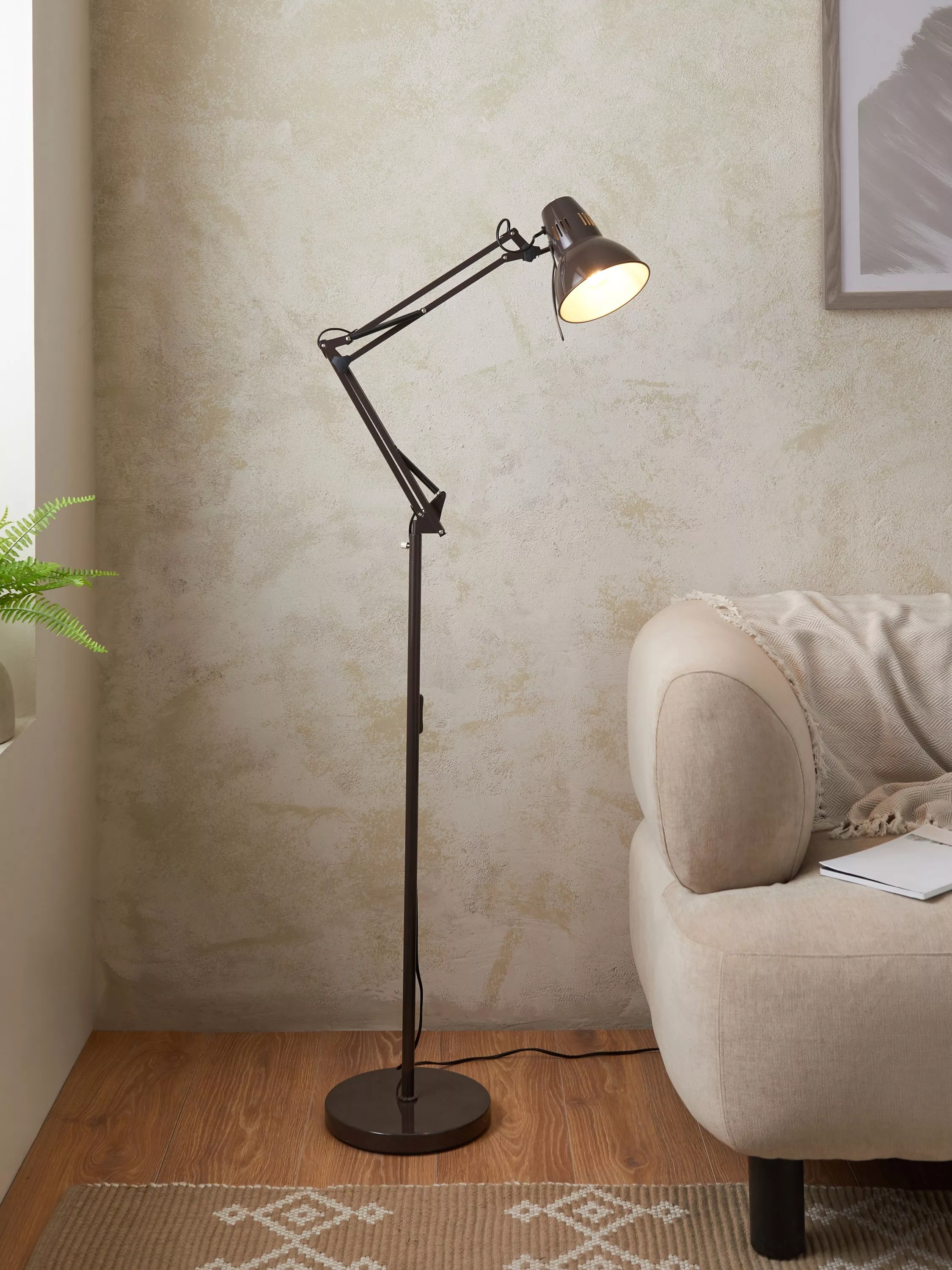 Black industrial floor lamp next to a cream sofa 