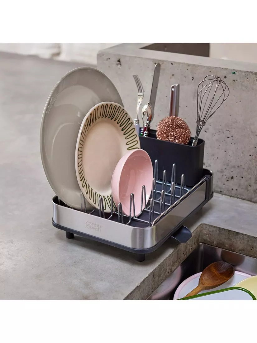 Compact kitchen dish drying rack with utensil holder, plates and bowls on a concrete worktop by the sink