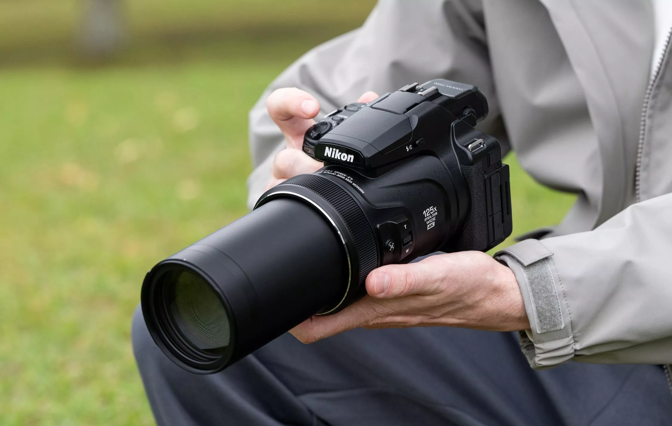 Person holding a Nikon bridge camera with long zoom lens outdoors, ideal for wildlife and sports photography