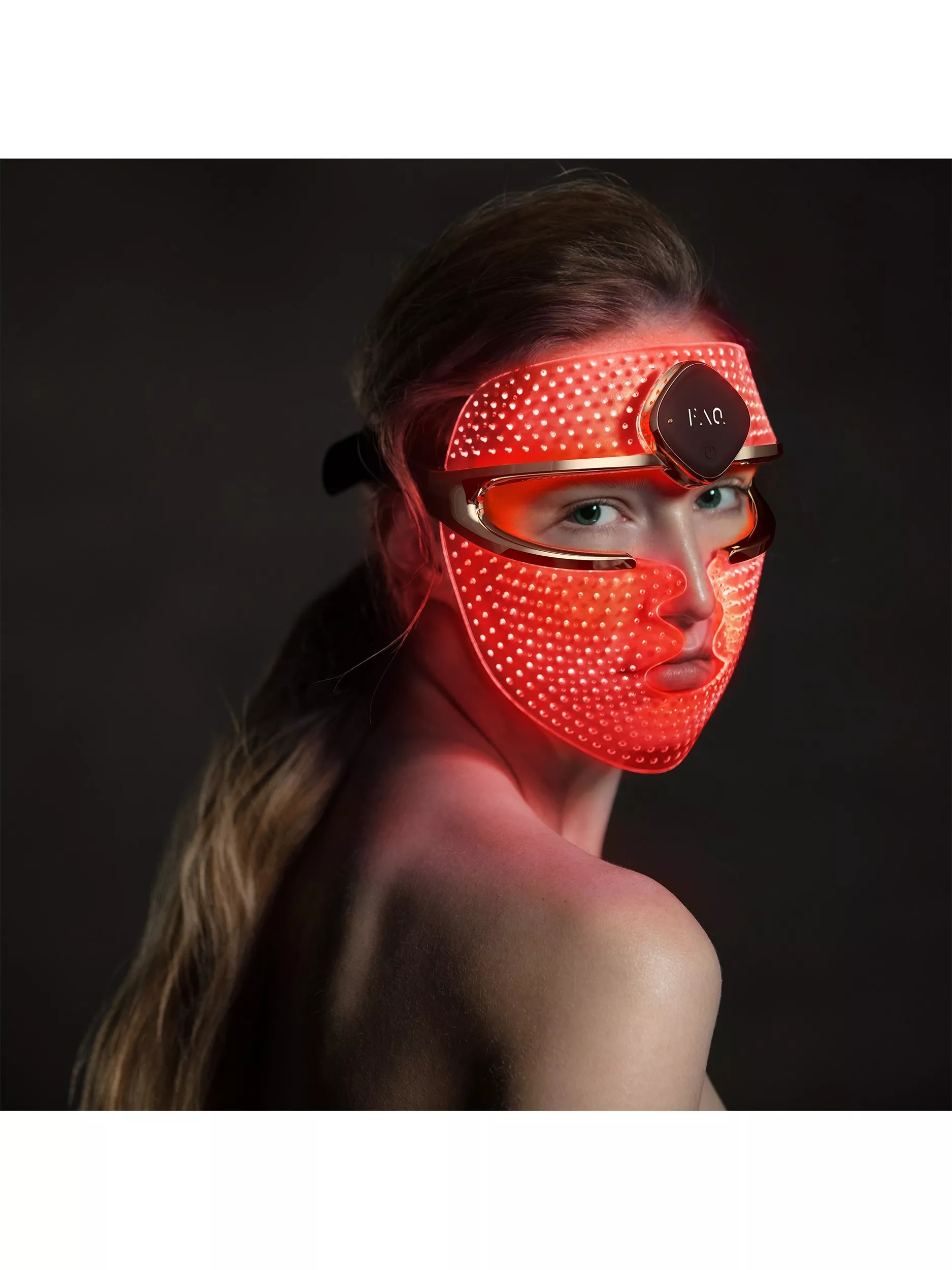 Woman wearing red LED light therapy face mask for skincare and anti-ageing treatment, studio portrait