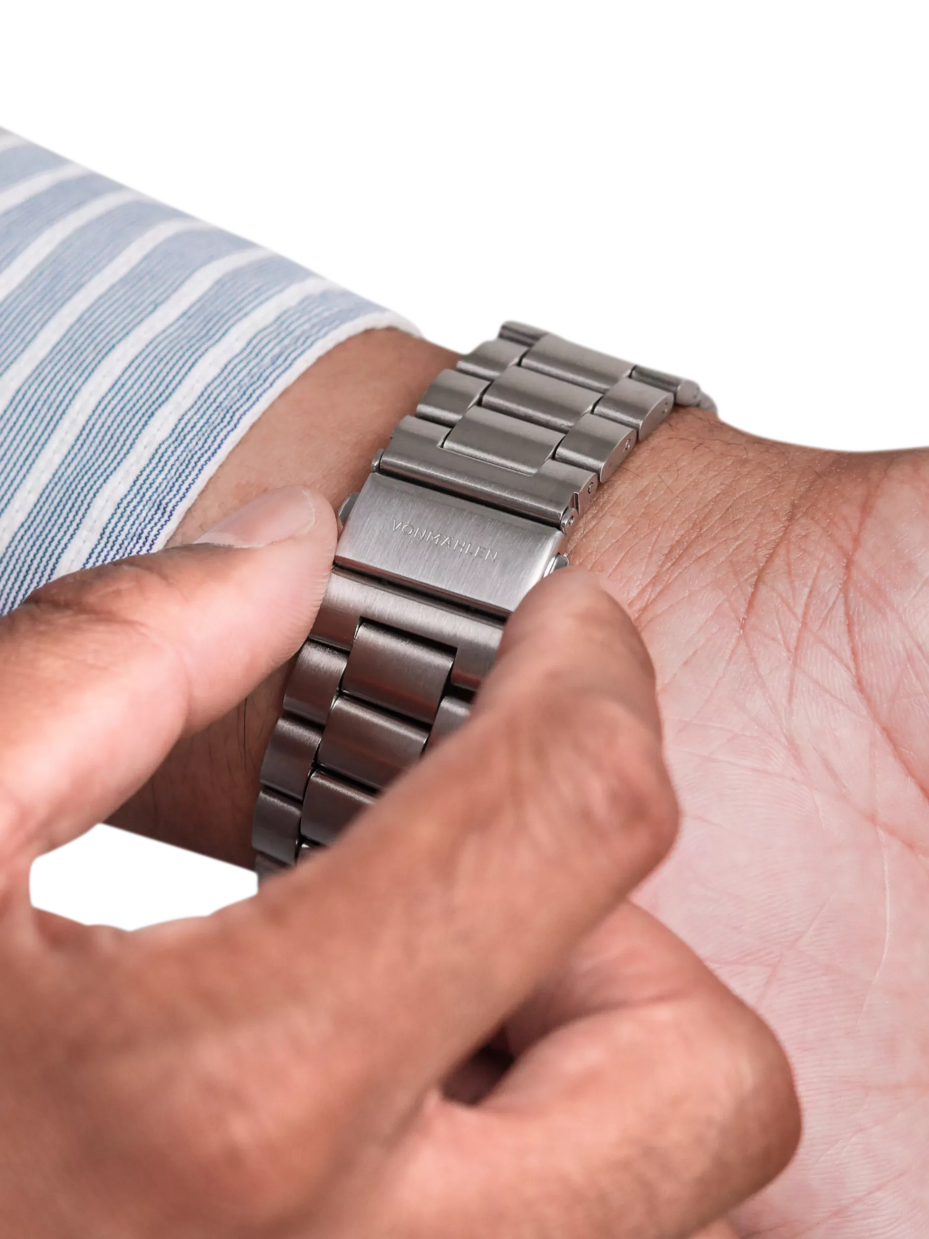 Close-up of hands fastening a stainless steel watch bracelet clasp on wrist, premium timepiece accessory detail