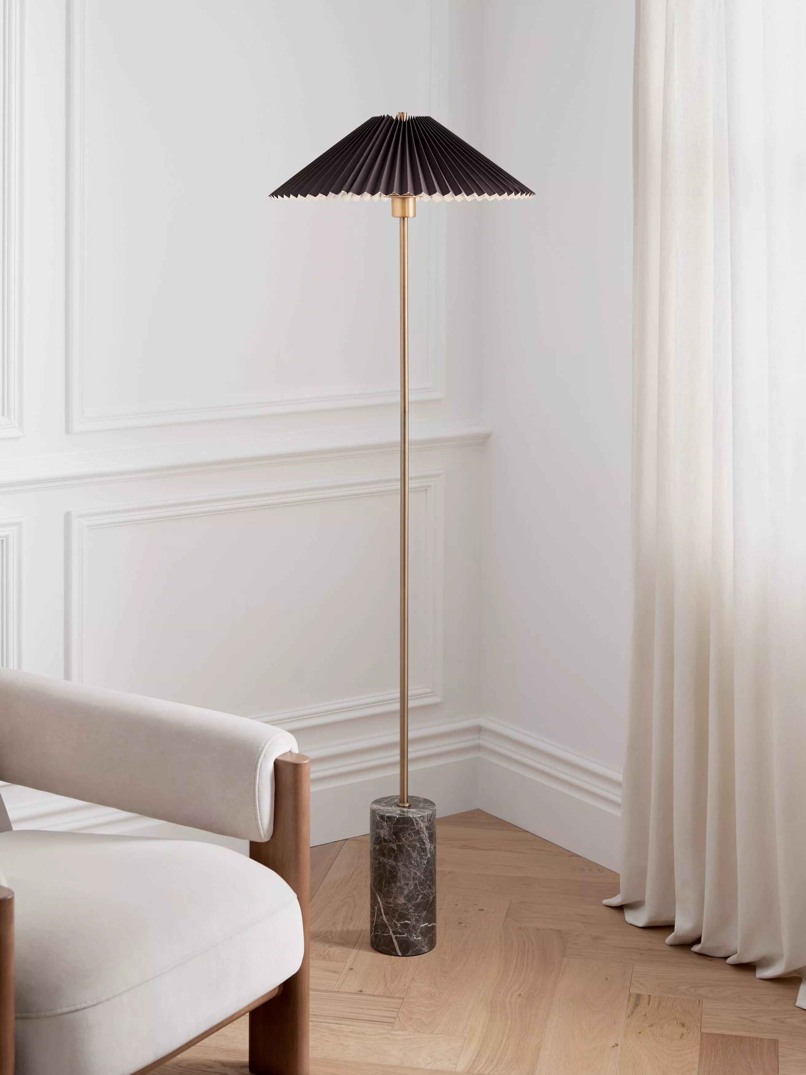 A modern adjustable floor lamp with a metallic finish illuminates a cosy living room corner with a beige sofa.