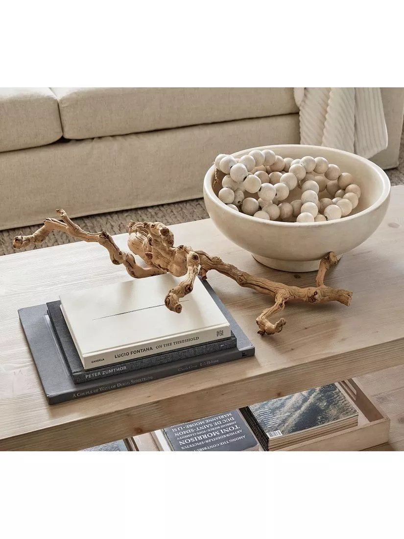 Neutral living room coffee table styling with wooden bowl, decorative beads, driftwood and stacked books