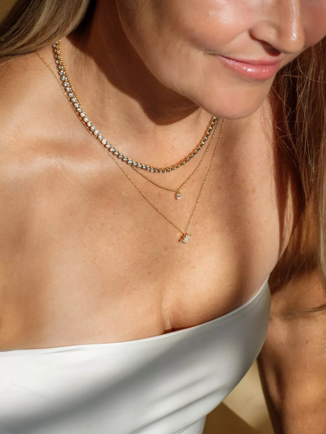 Gold chain necklace with a teardrop-shaped, vibrant green gemstone pendant set in gold. Elegant and modern design.