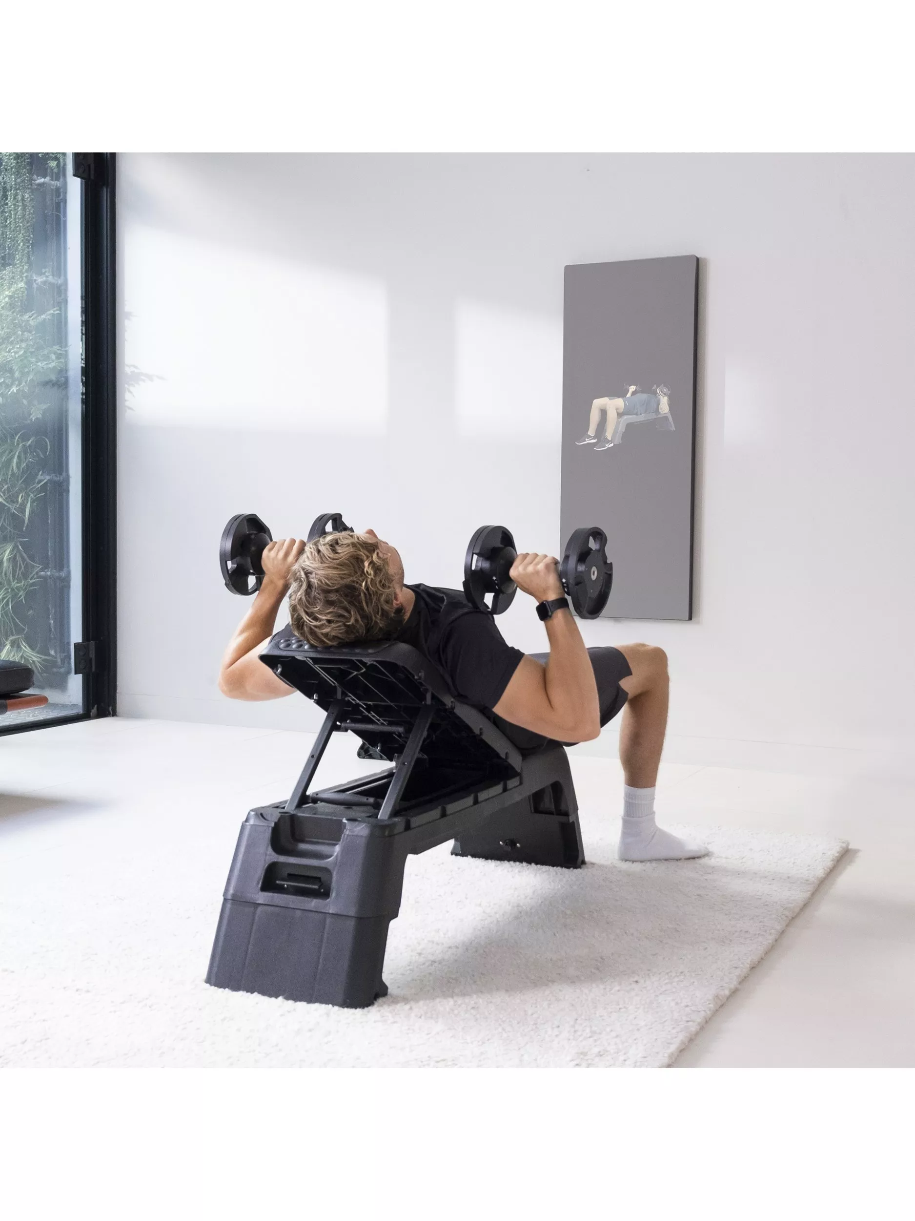 Man doing incline dumbbell bench press on adjustable workout bench in bright home gym for strength training