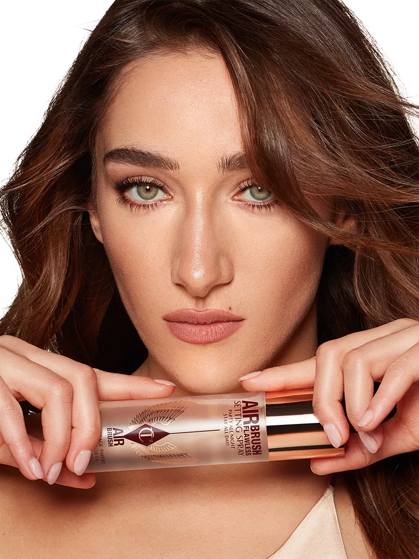 Close-up beauty portrait of woman holding Charlotte Tilbury Airbrush Flawless setting spray, studio shot