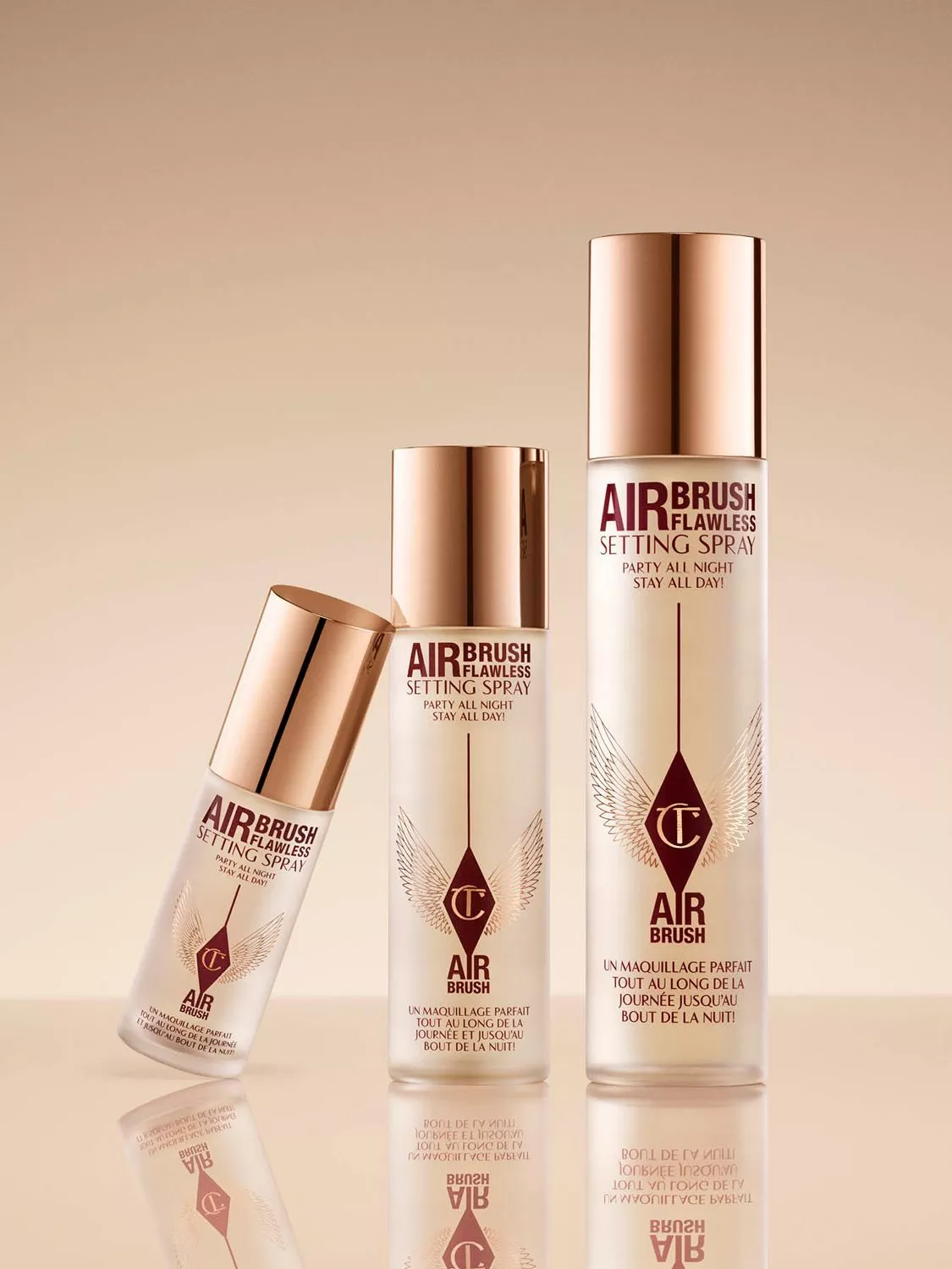 Charlotte Tilbury Airbrush Flawless Setting Spray bottles with rose-gold caps on beige studio background.