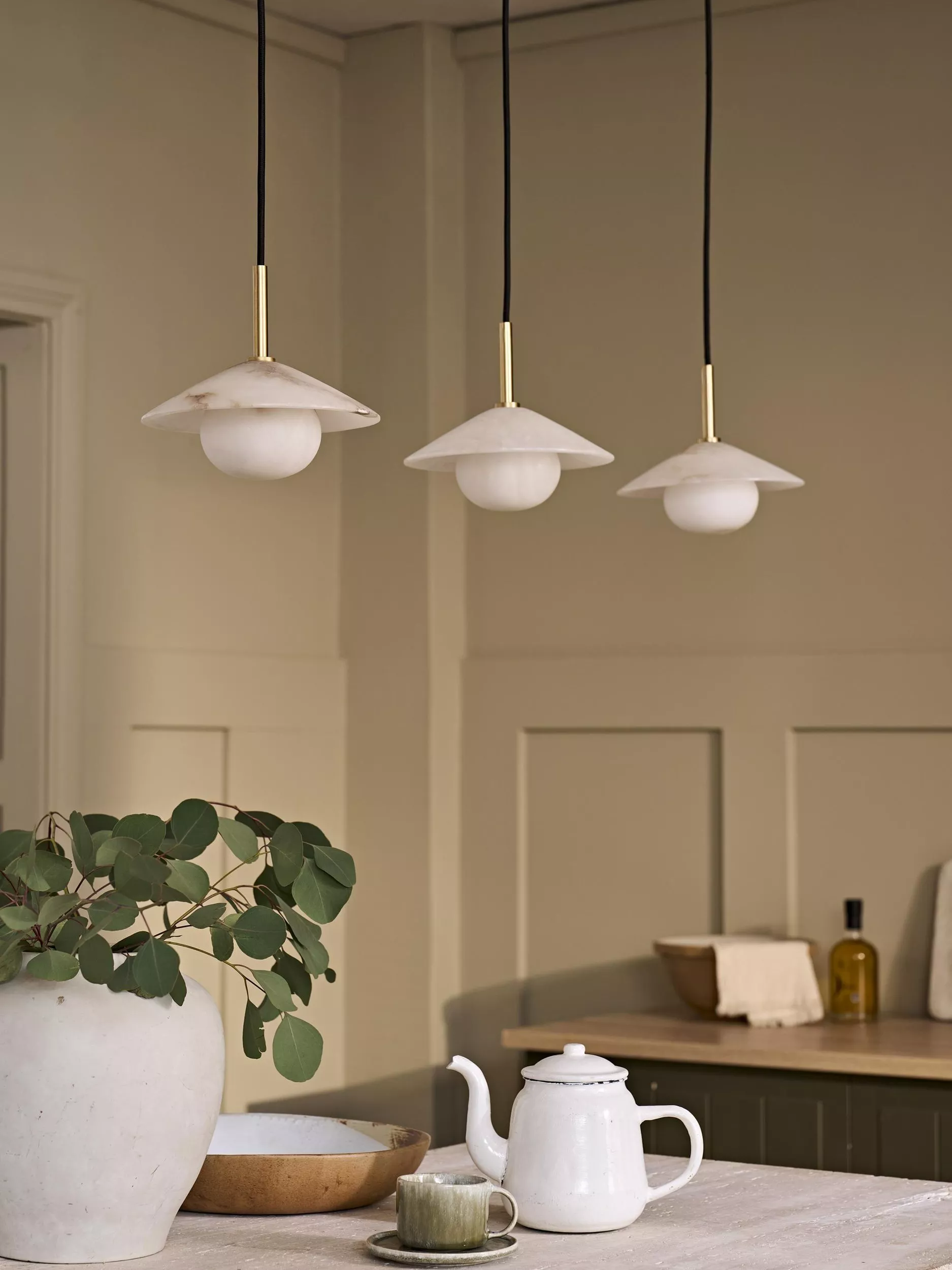 Modern fabric pendant ceiling light in a cosy living room above a brown sofa with neutral décor and vase