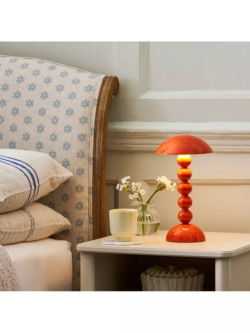 Modern cream boucle armchair with cushions beside brass floor lamp in bright living room by garden windows