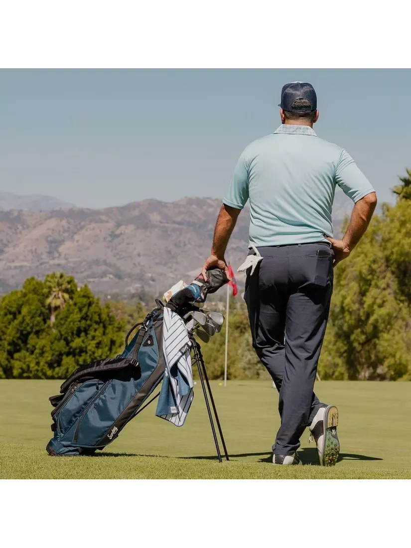 man standing on golf course with golf bag and clubs