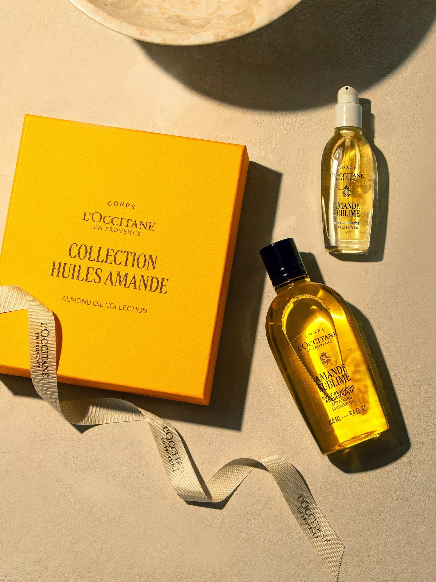 L’Occitane almond oil collection gift box with Amande Sublime shower and skin oils on a sunlit surface