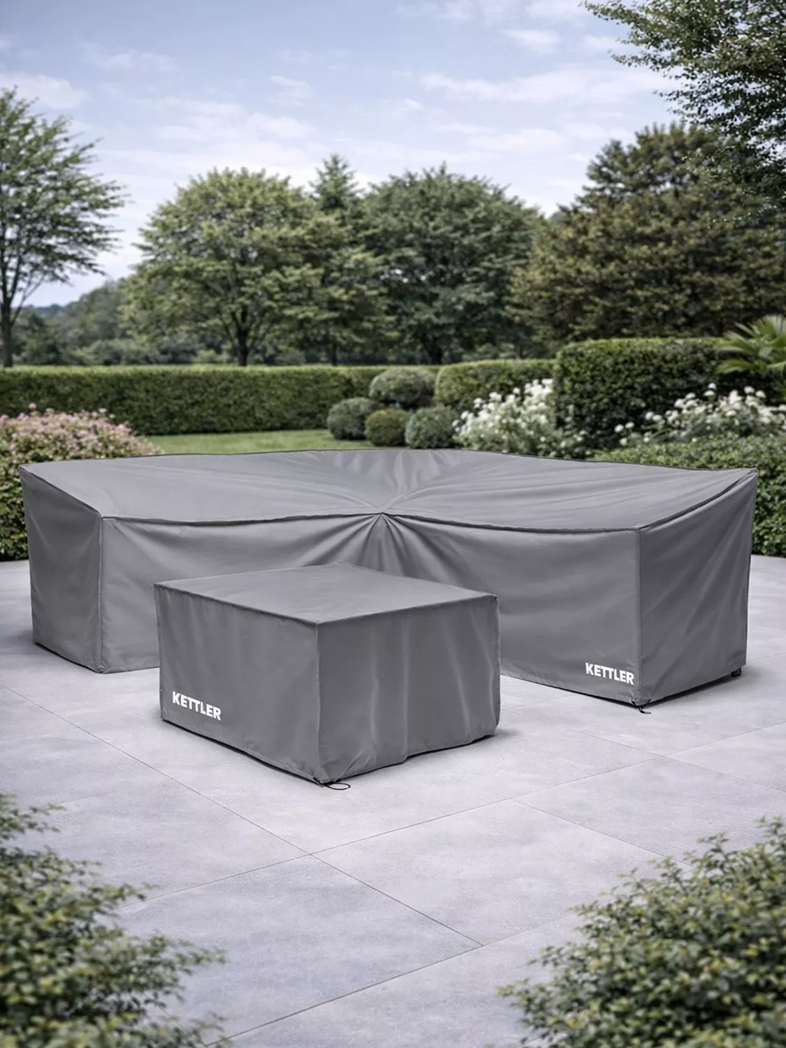 Grey KETTLER outdoor furniture covers on patio, protecting garden corner sofa and footstool in summer garden