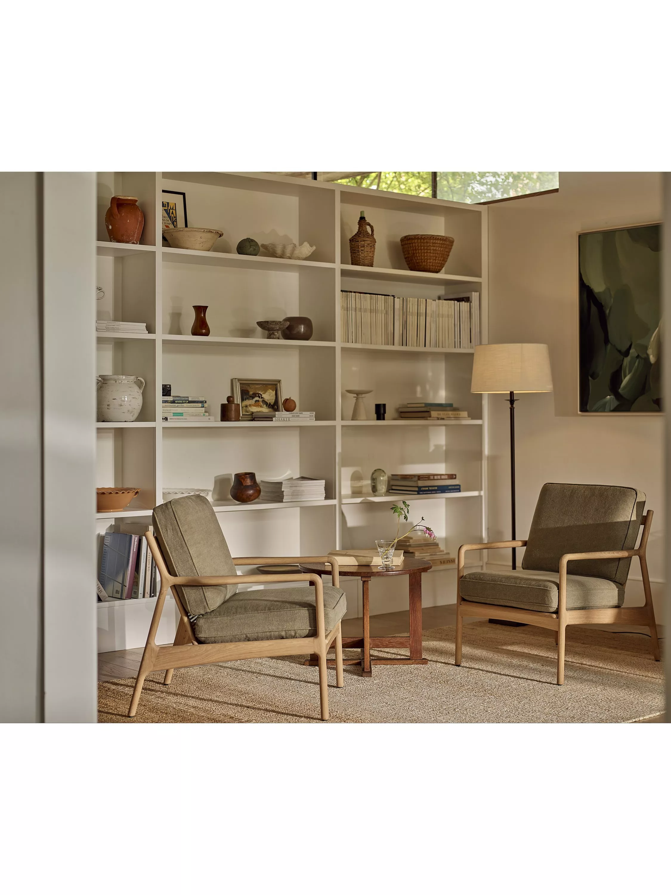 Modern living room with two upholstered armchairs, round coffee table, floor lamp and built-in bookcase shelving