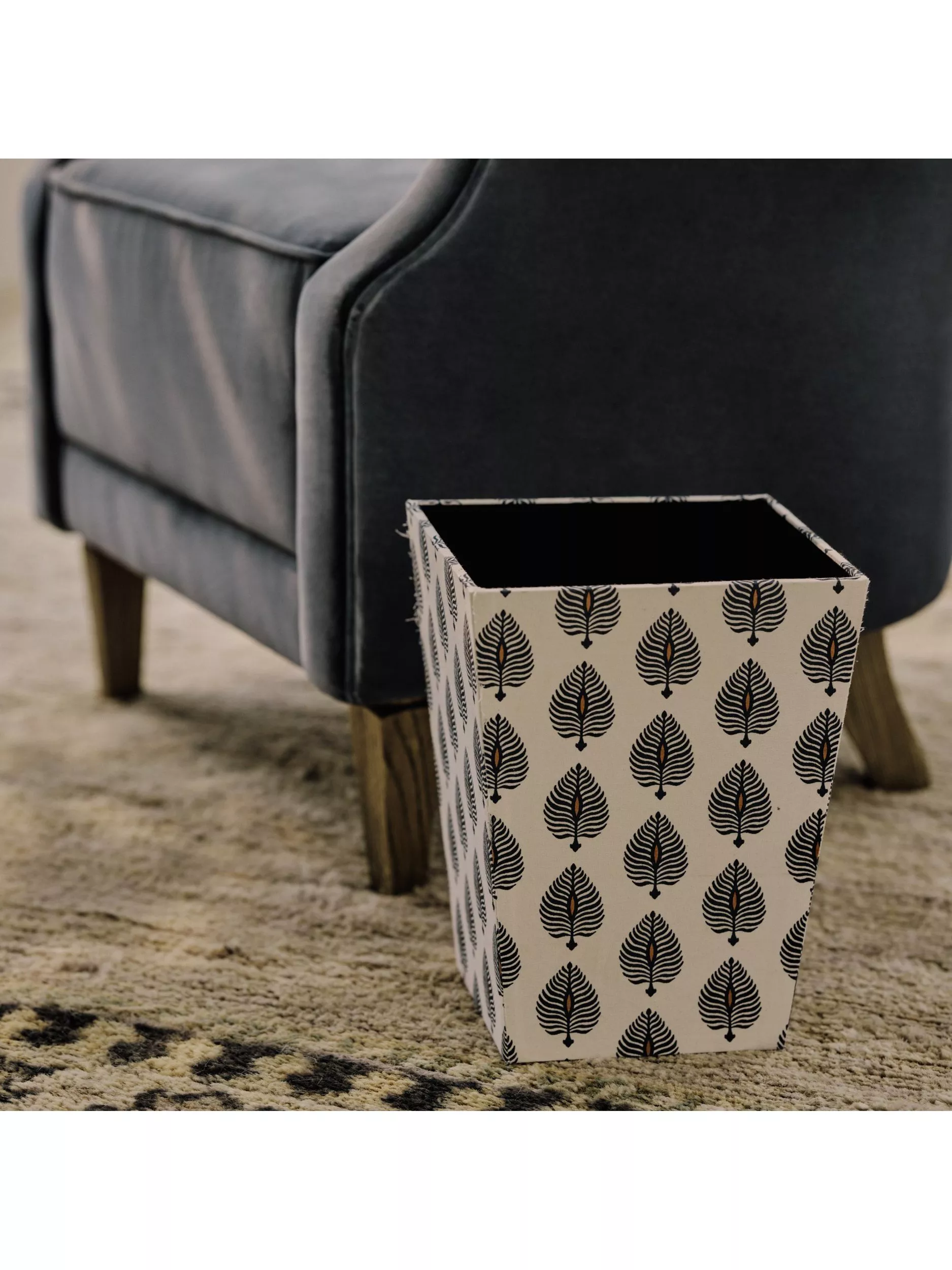 Patterned storage box beside grey armchair on rug, stylish living room organiser for home décor and tidying