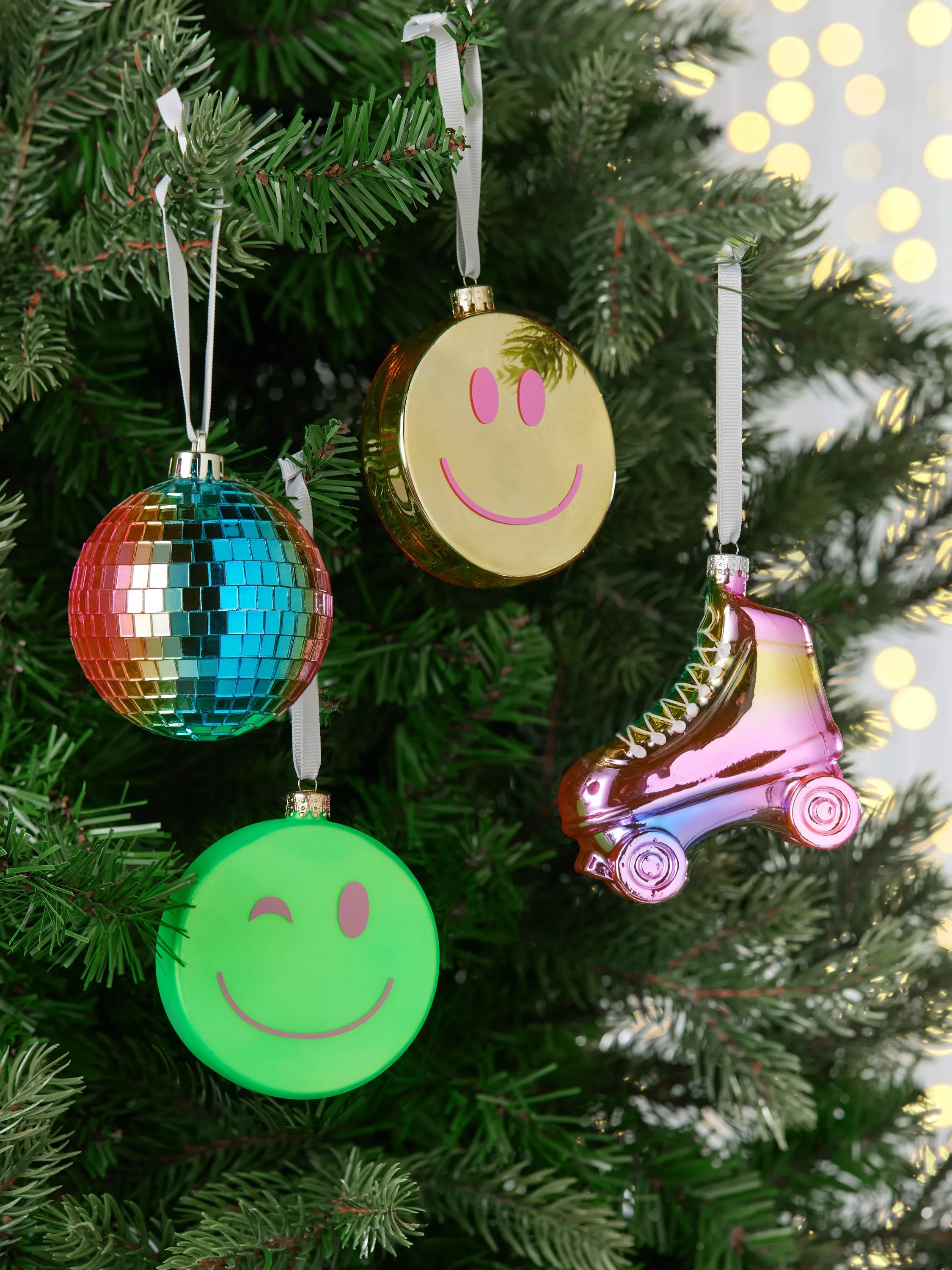 Colourful Christmas tree decorations with smiley face baubles, disco ball ornament and roller skate, close-up.