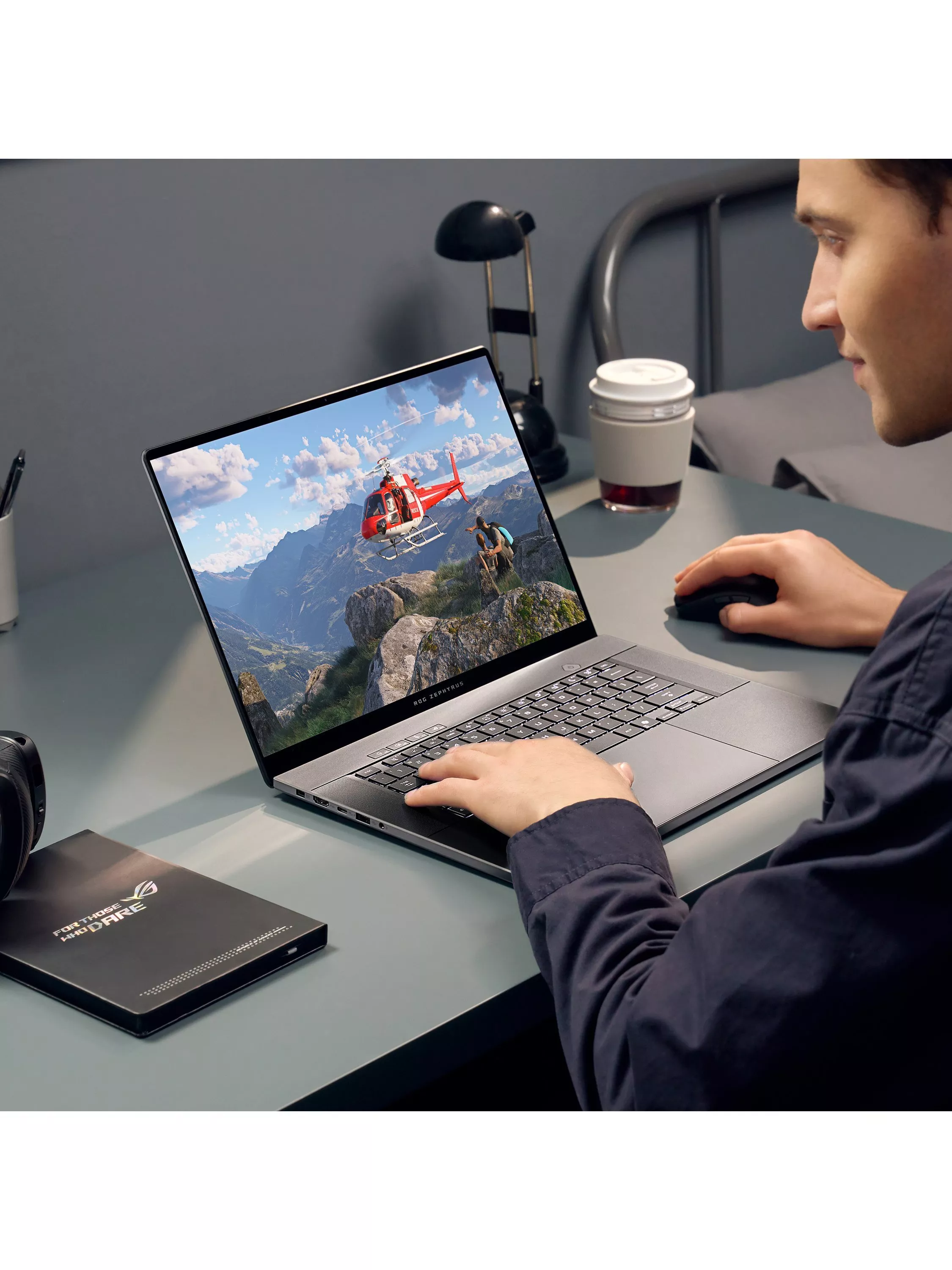 Person using a gaming laptop at a desk, with helicopter adventure game on screen and coffee cup nearby