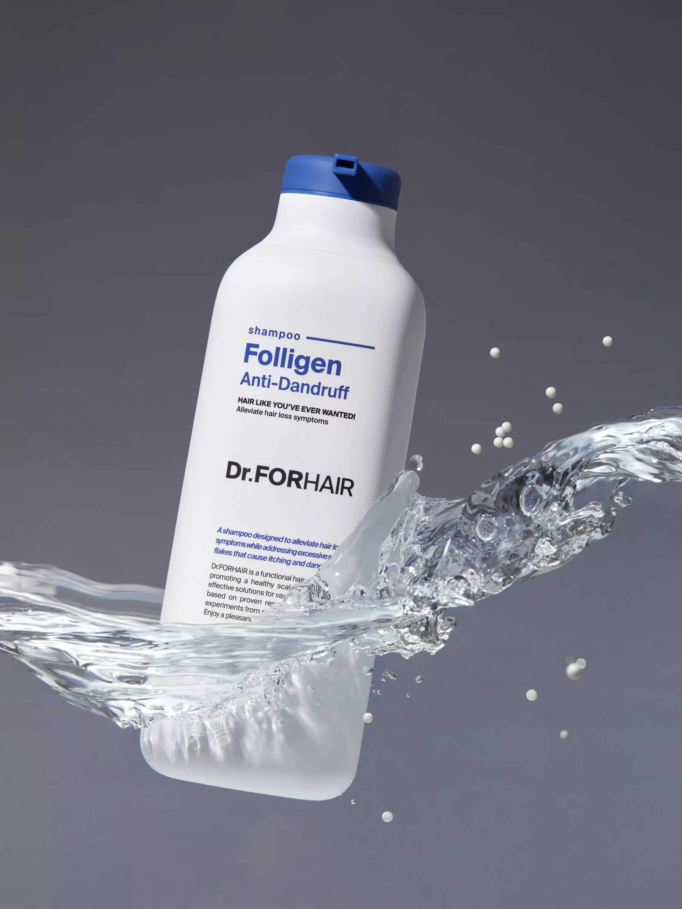 Dr.FORHAIR Folligen anti-dandruff shampoo bottle with blue cap splashing through water on grey background