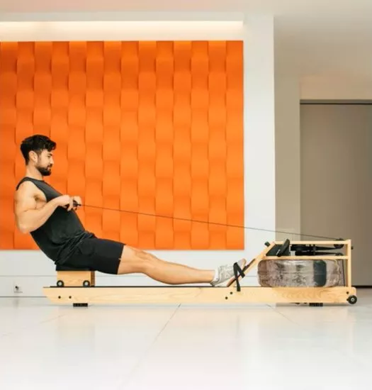 Woman using a smart home rowing machine with screen, exercising in a bright modern living room interior