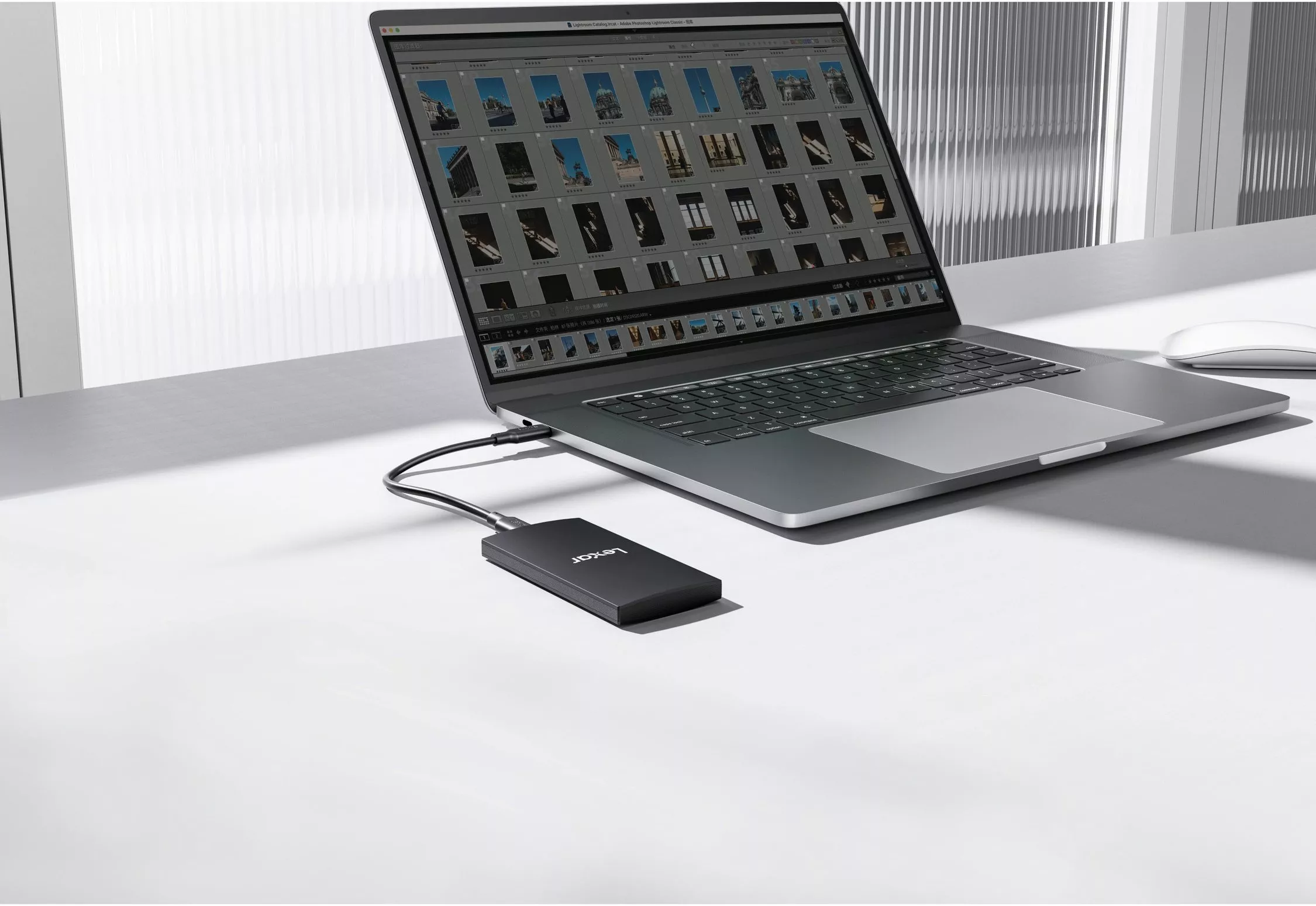 Laptop running photo editing software with an external portable SSD connected via USB-C on a modern desk