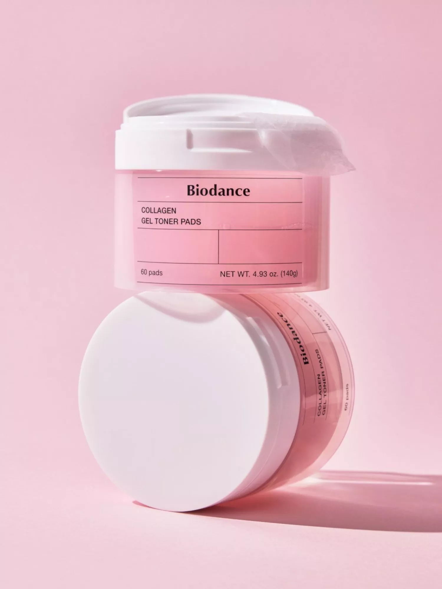 Biodance collagen gel toner pads in pink jar with white lid, stacked packaging on pastel pink background