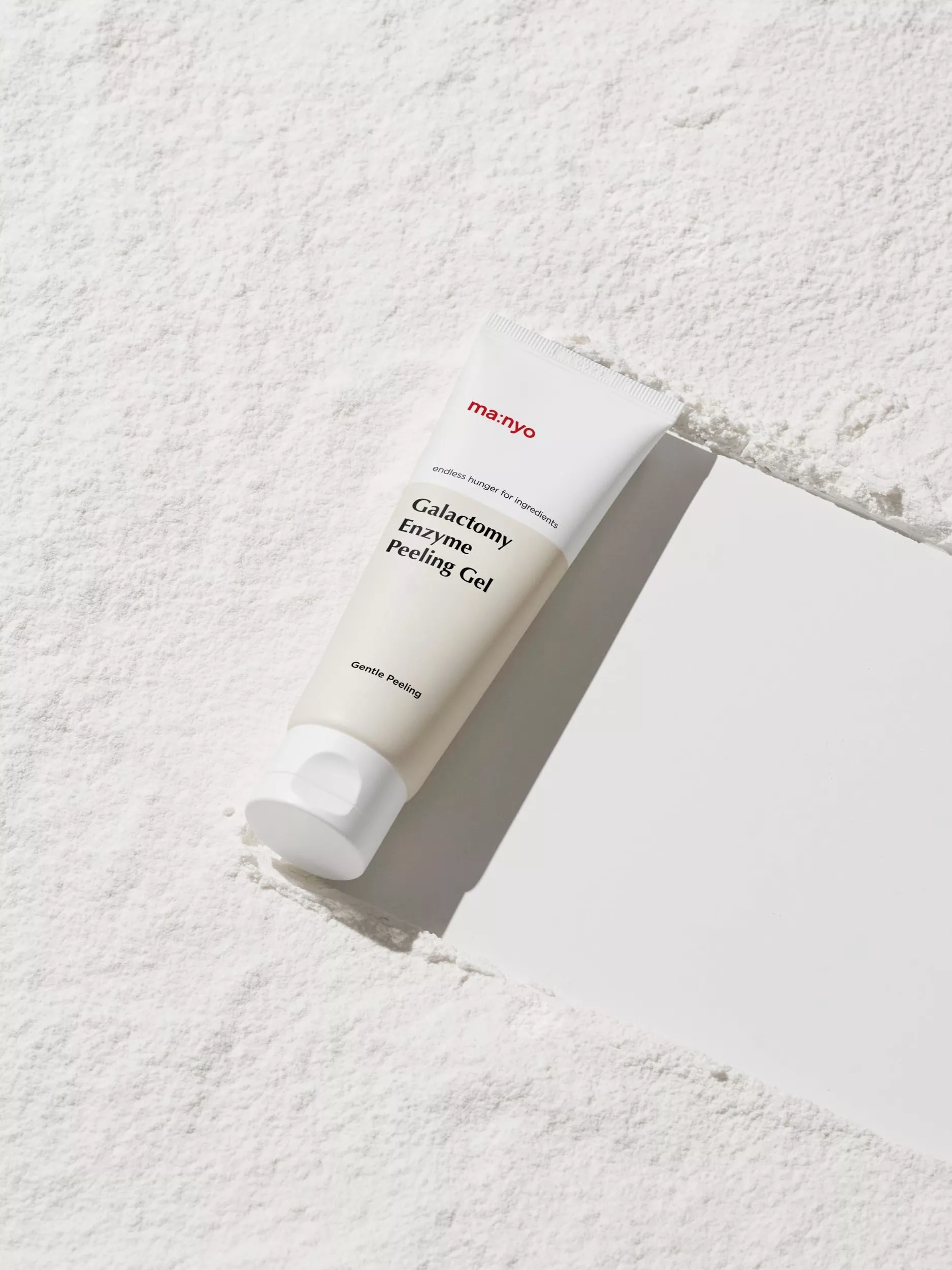 ma:nyo Galactomy Enzyme Peeling Gel tube on textured white surface, minimalist Korean skincare product photo