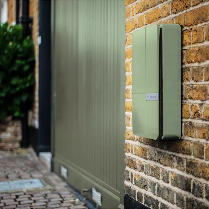 Wall-mounted smart parcel delivery box on brick wall by front gate, secure home package drop-off solution