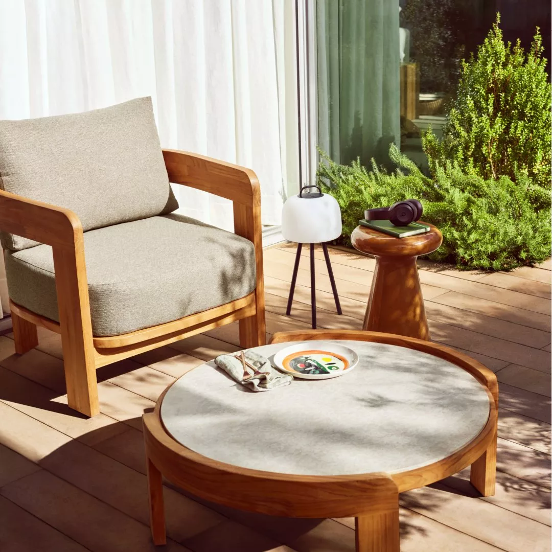 Modern outdoor dining set with wooden table and cushioned chairs in a Mediterranean garden patio setting