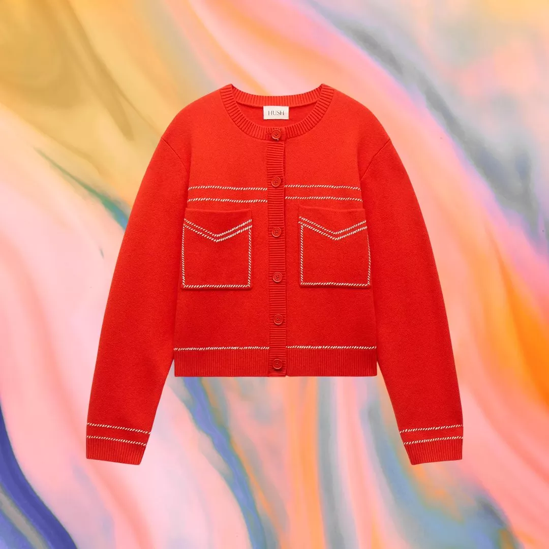 A vibrant red cardigan with white stitching and pockets, set against a colourful, abstract background.
