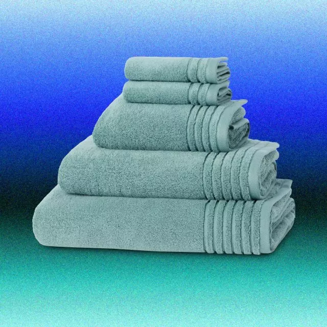 Stacked seafoam green cotton bath towels set on blue gradient background, soft absorbent bathroom linen collection