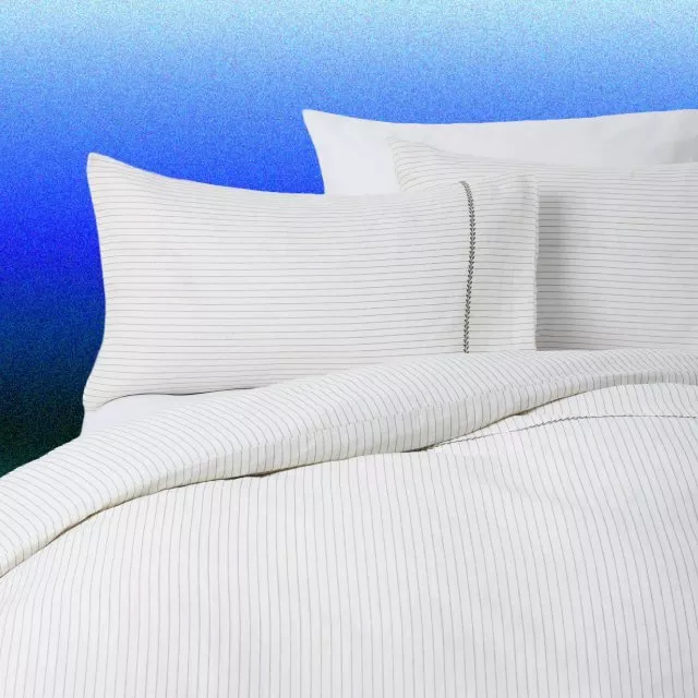 White pinstripe duvet cover and pillowcases on bed, modern minimalist bedding set against blue background