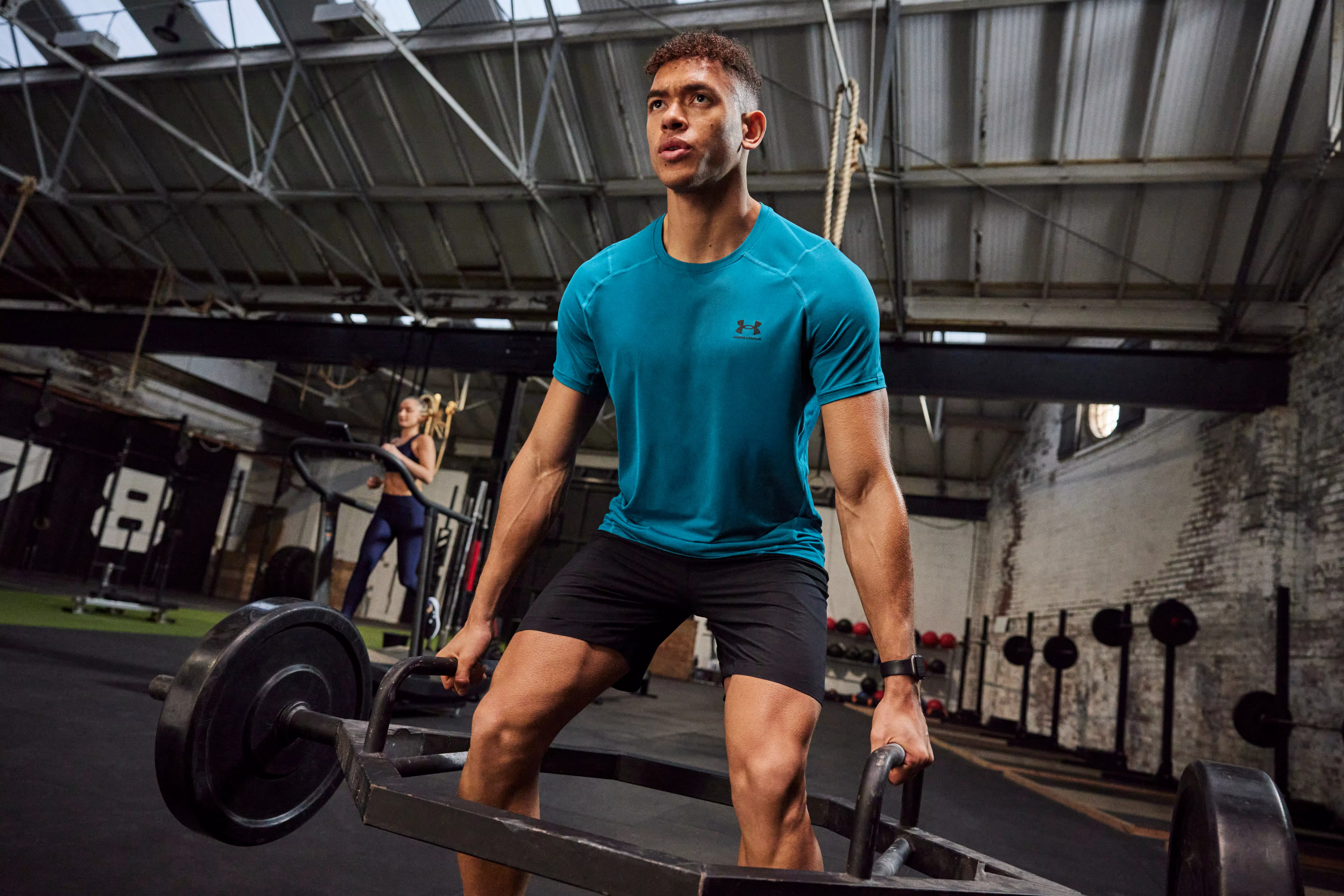 Man lifting weights in the gym in shorts and a blue t-shirt