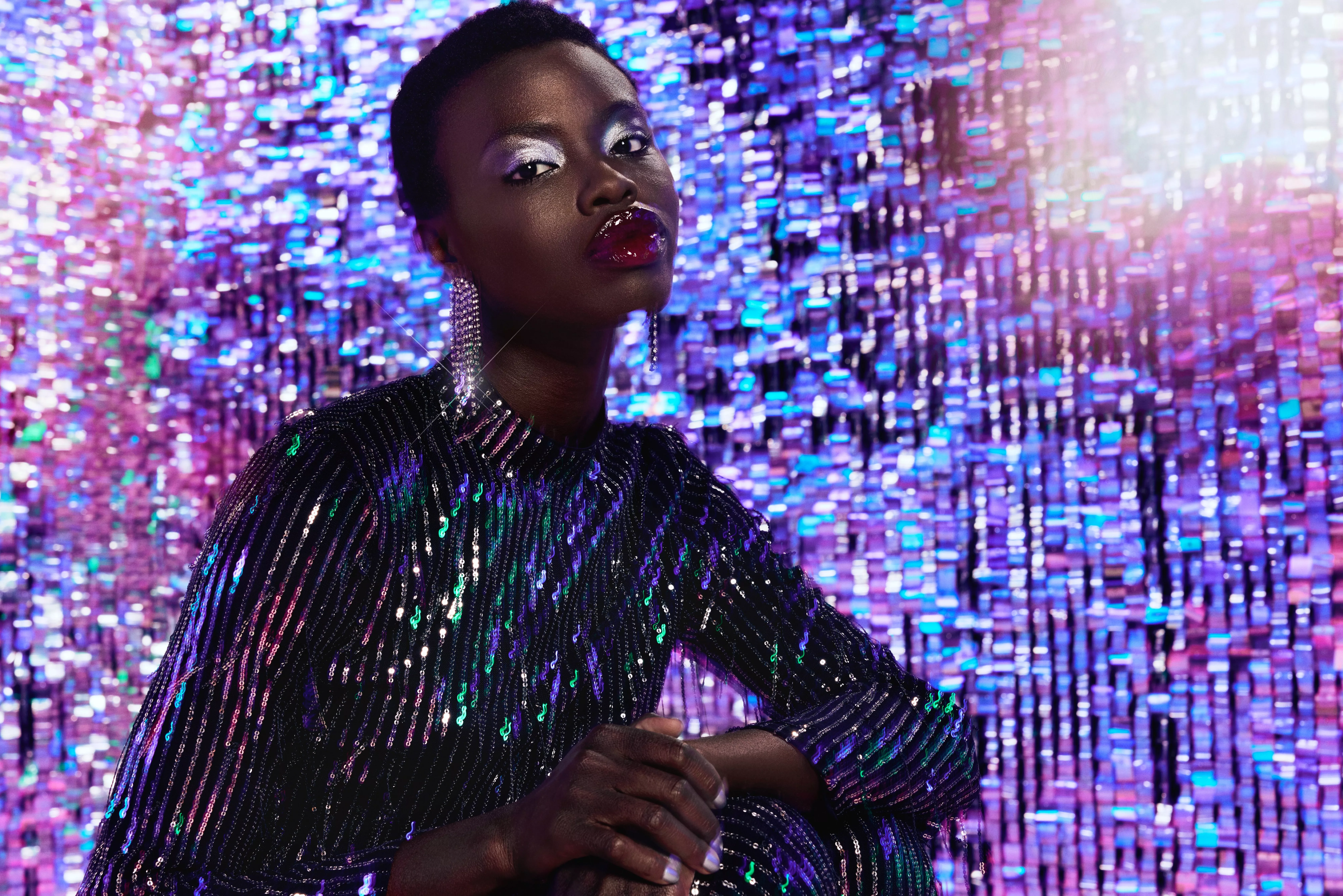 Woman wearing a sequin green and silver dress on a sparkly background