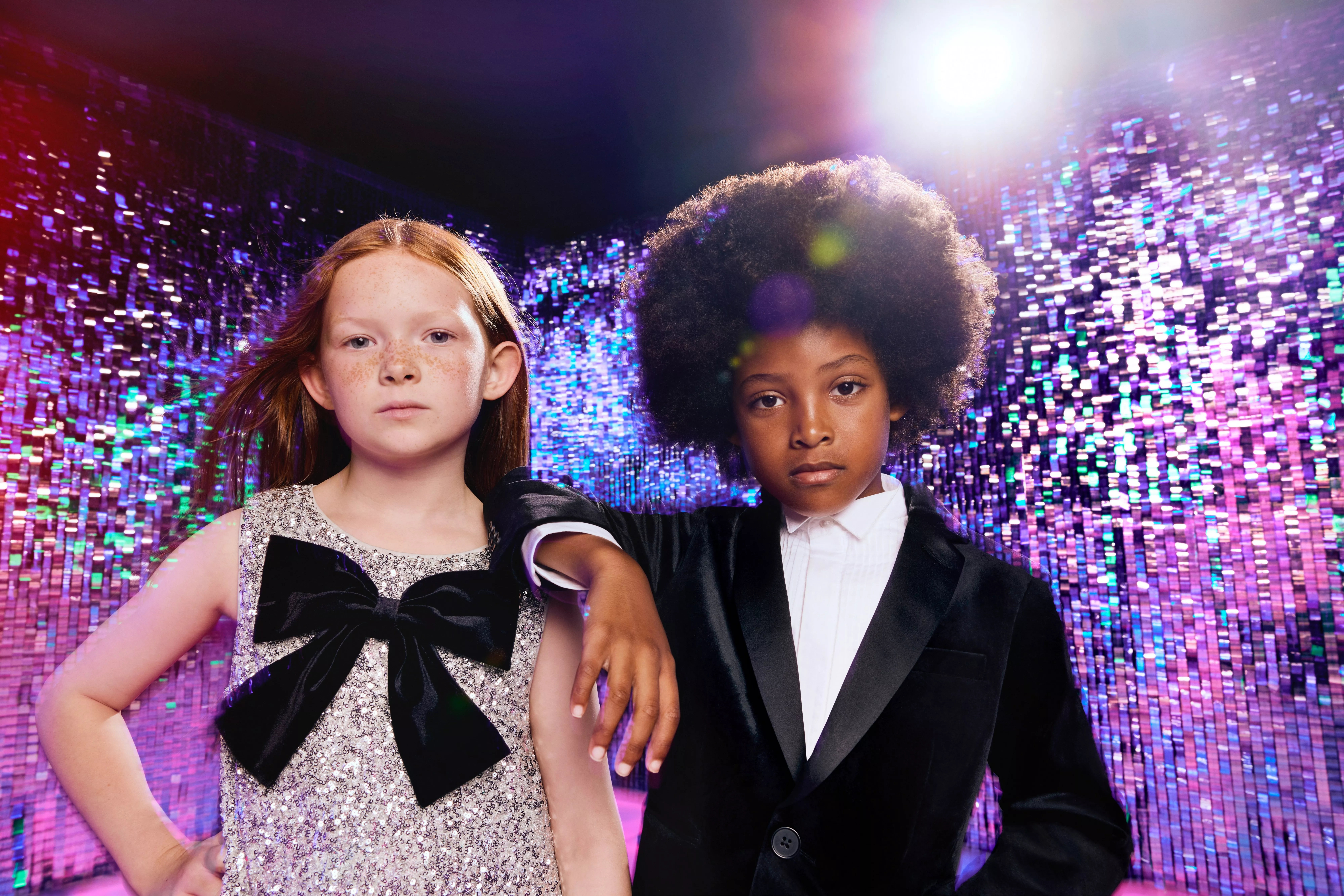 boy and girl wearing partywear on a sparkly background