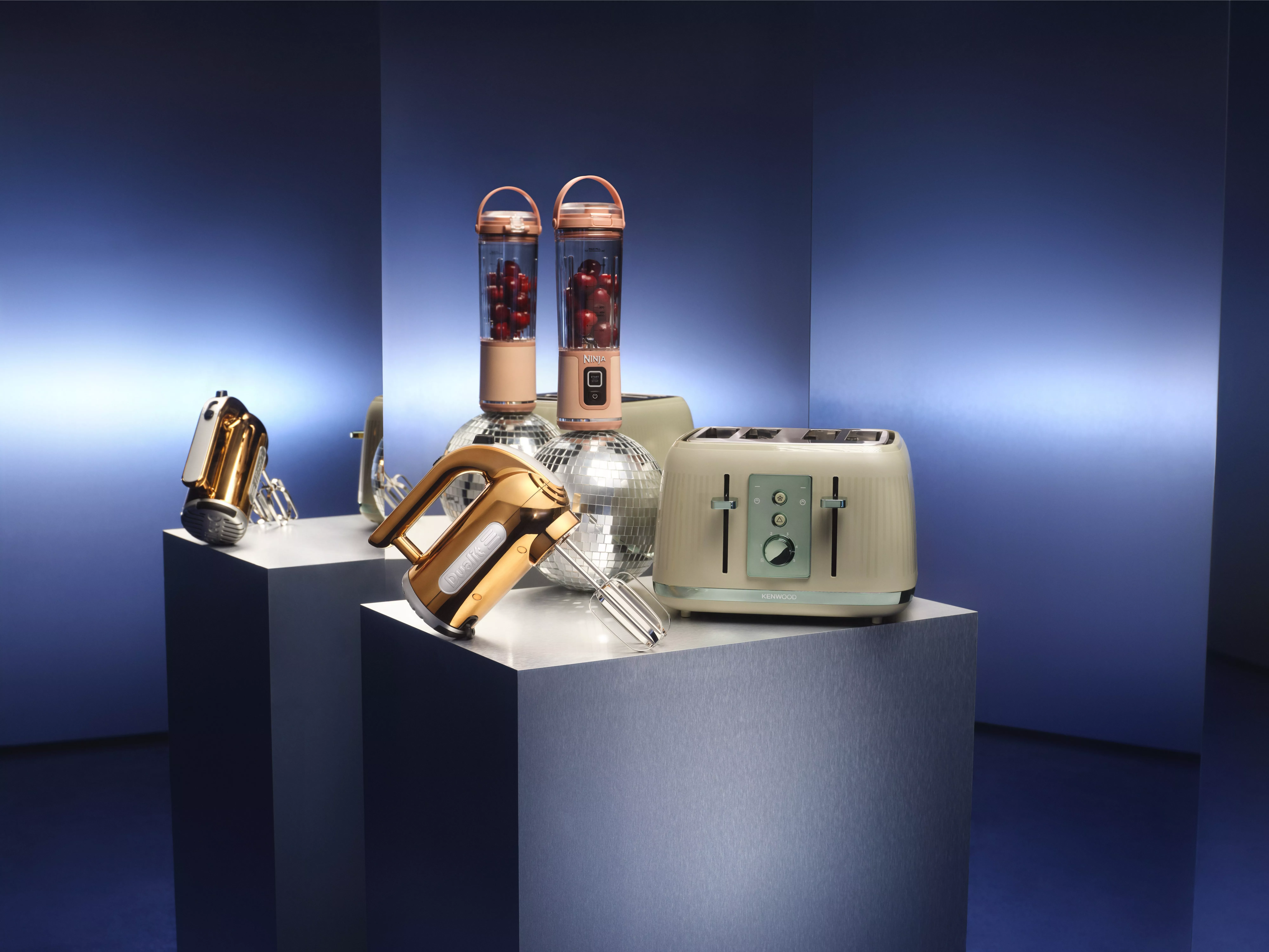 A selection of kitchen gadgets on a plinth in front of a mirrored background