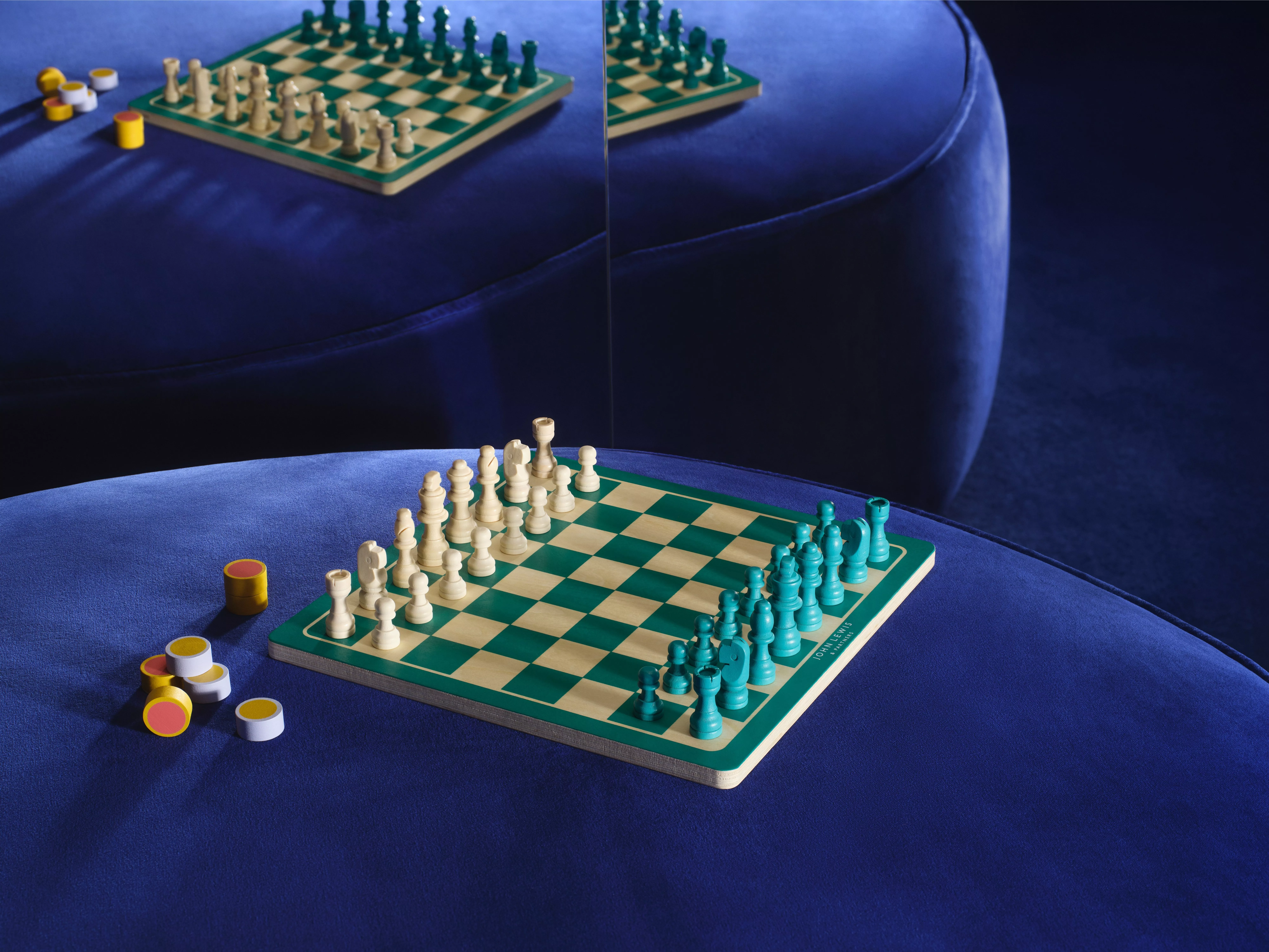 A green and white chess set on a blue velvet stool