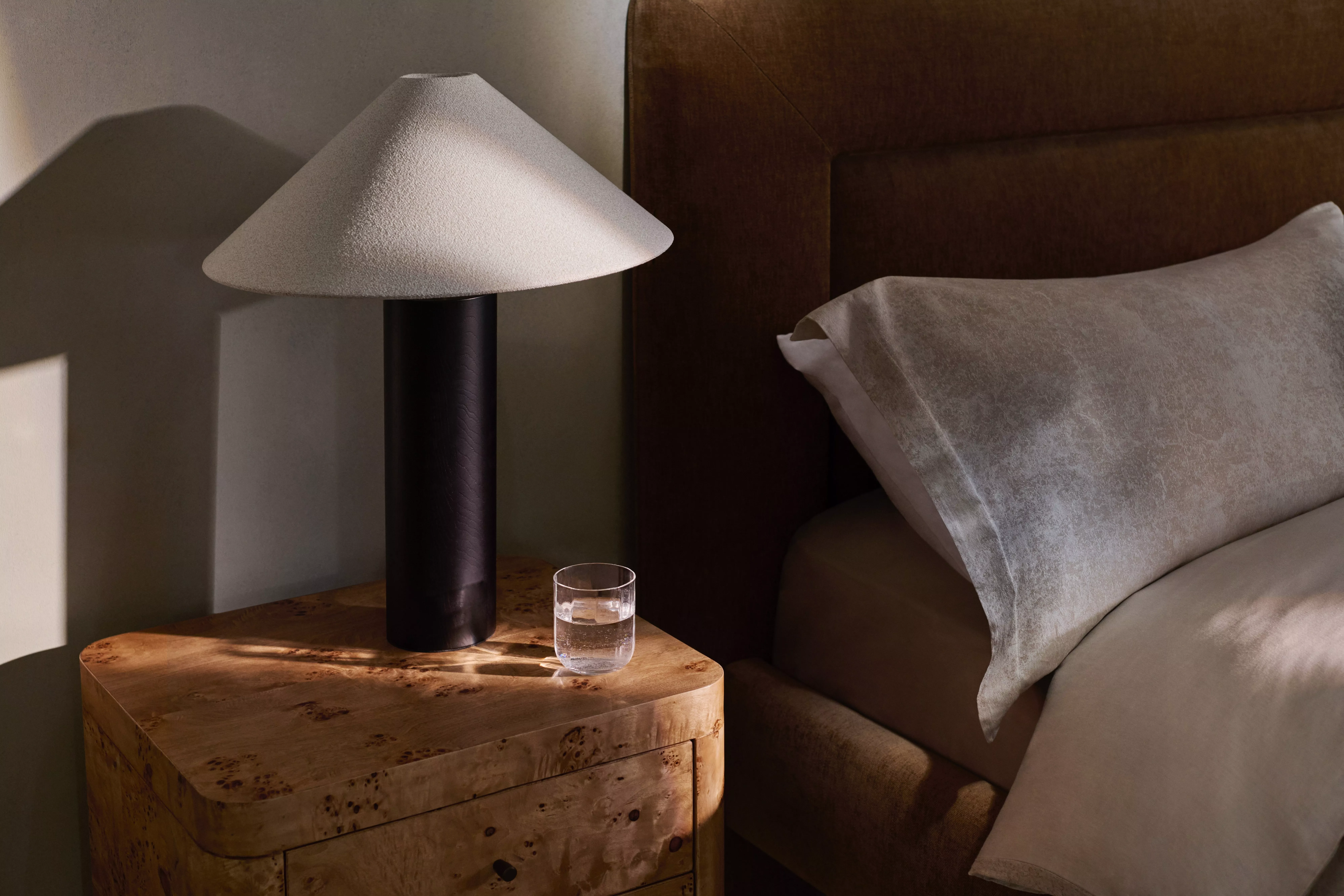 Brown lamp with cream lampshade on a wooden bedside table 