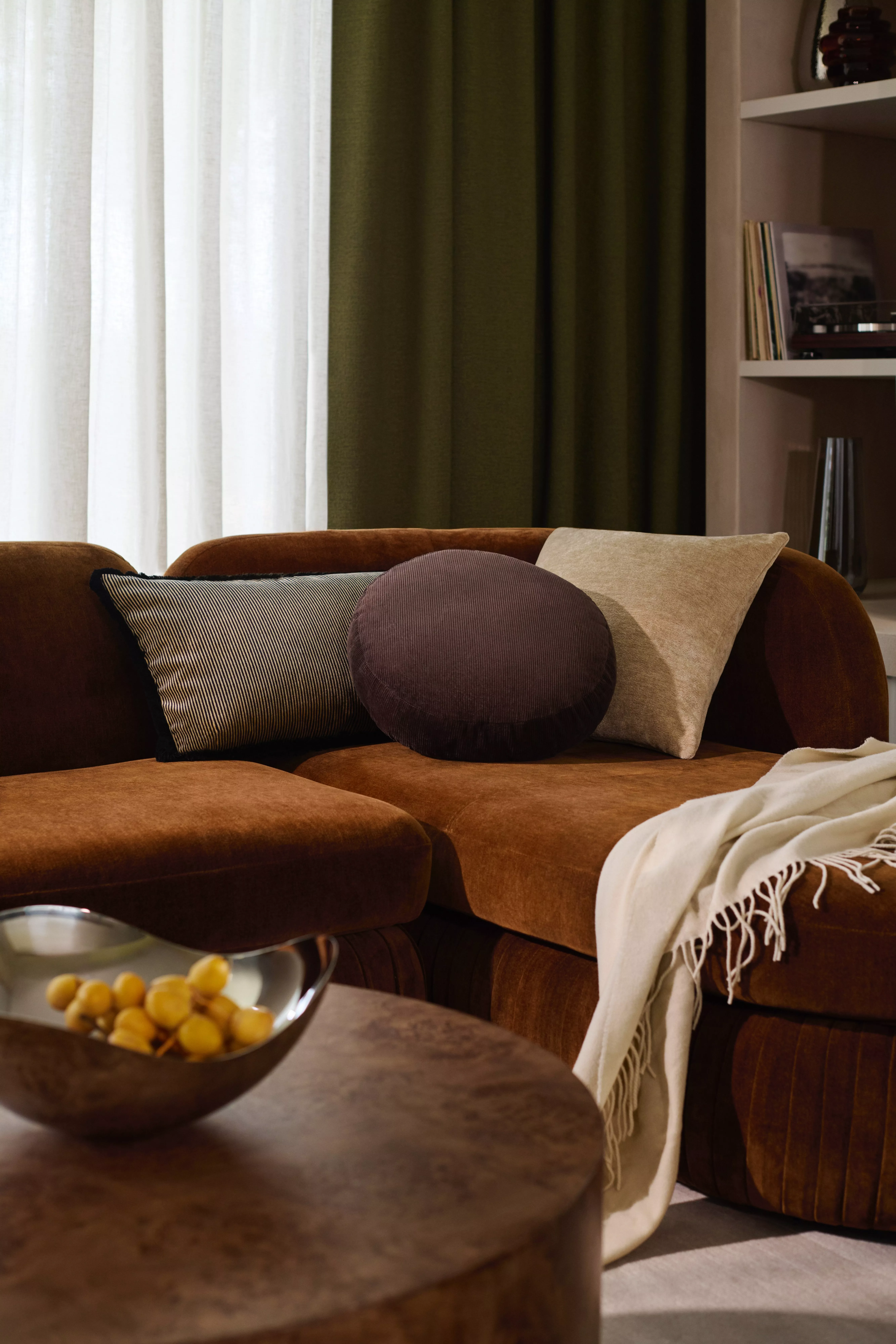 Brown corner sofa with decorative cushions and a cream throw