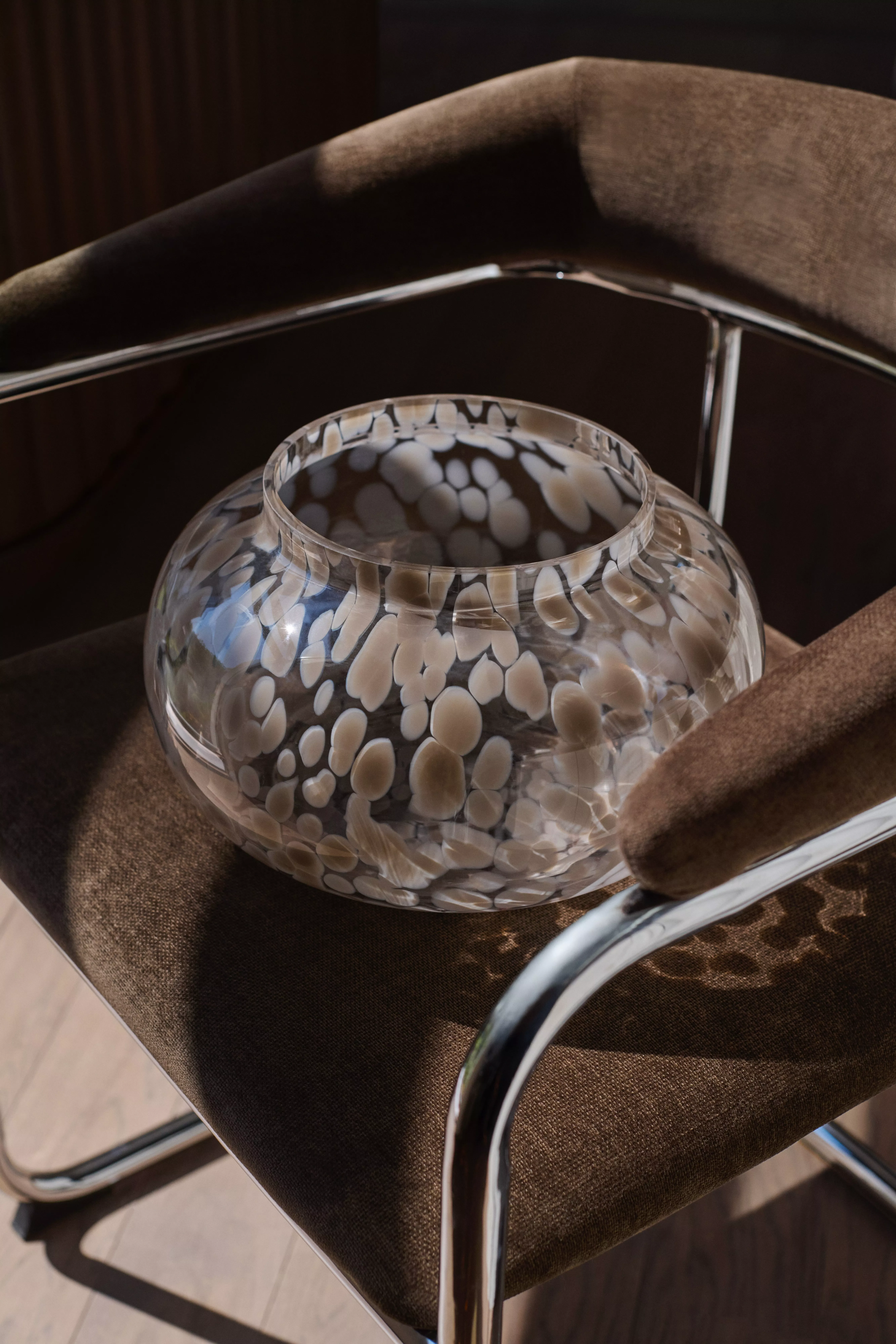 Mottled gray glass decorative bowl on velvet and metal chair
