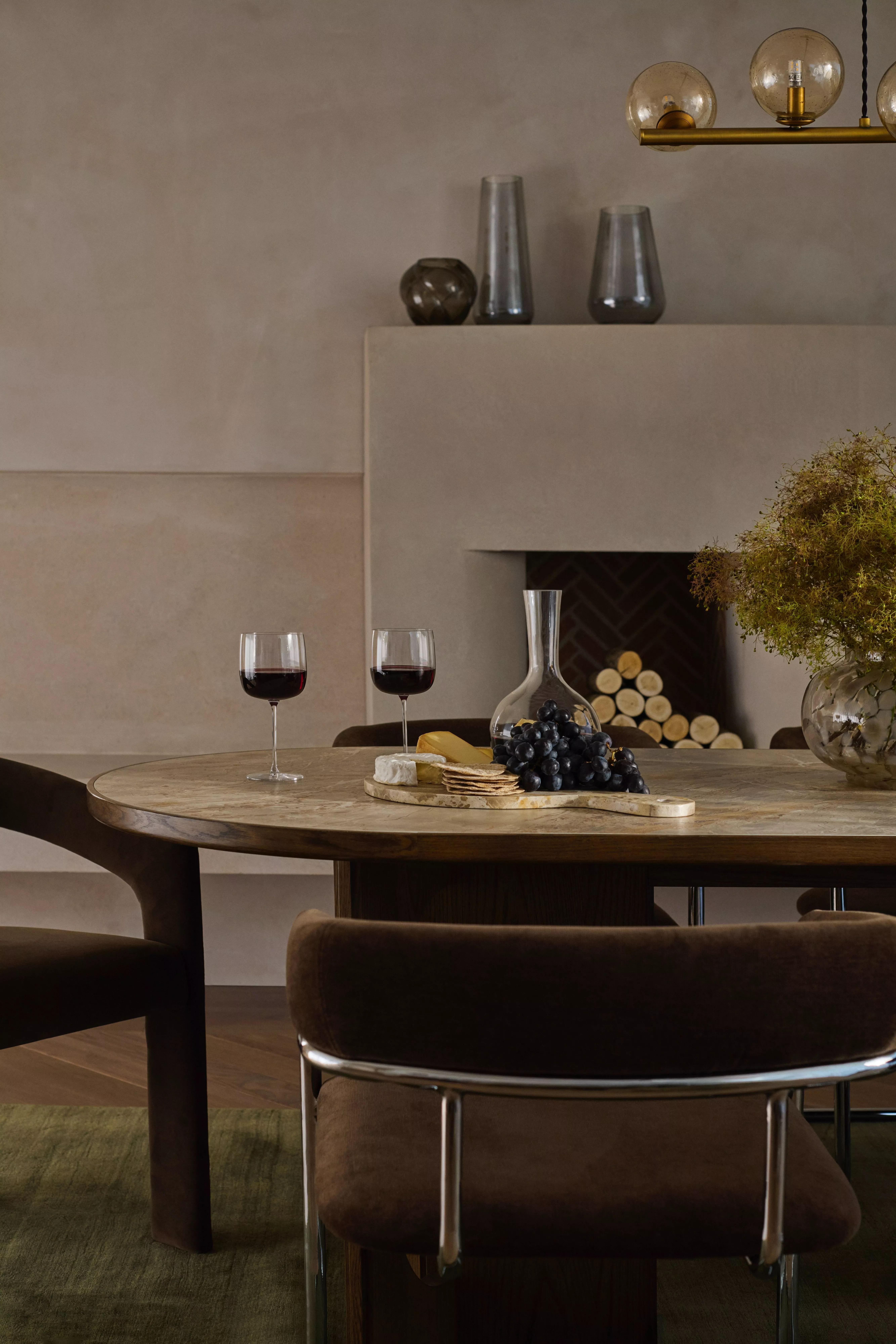 A dining room with a marble table and brown velvet and chrome chairs on a green rug