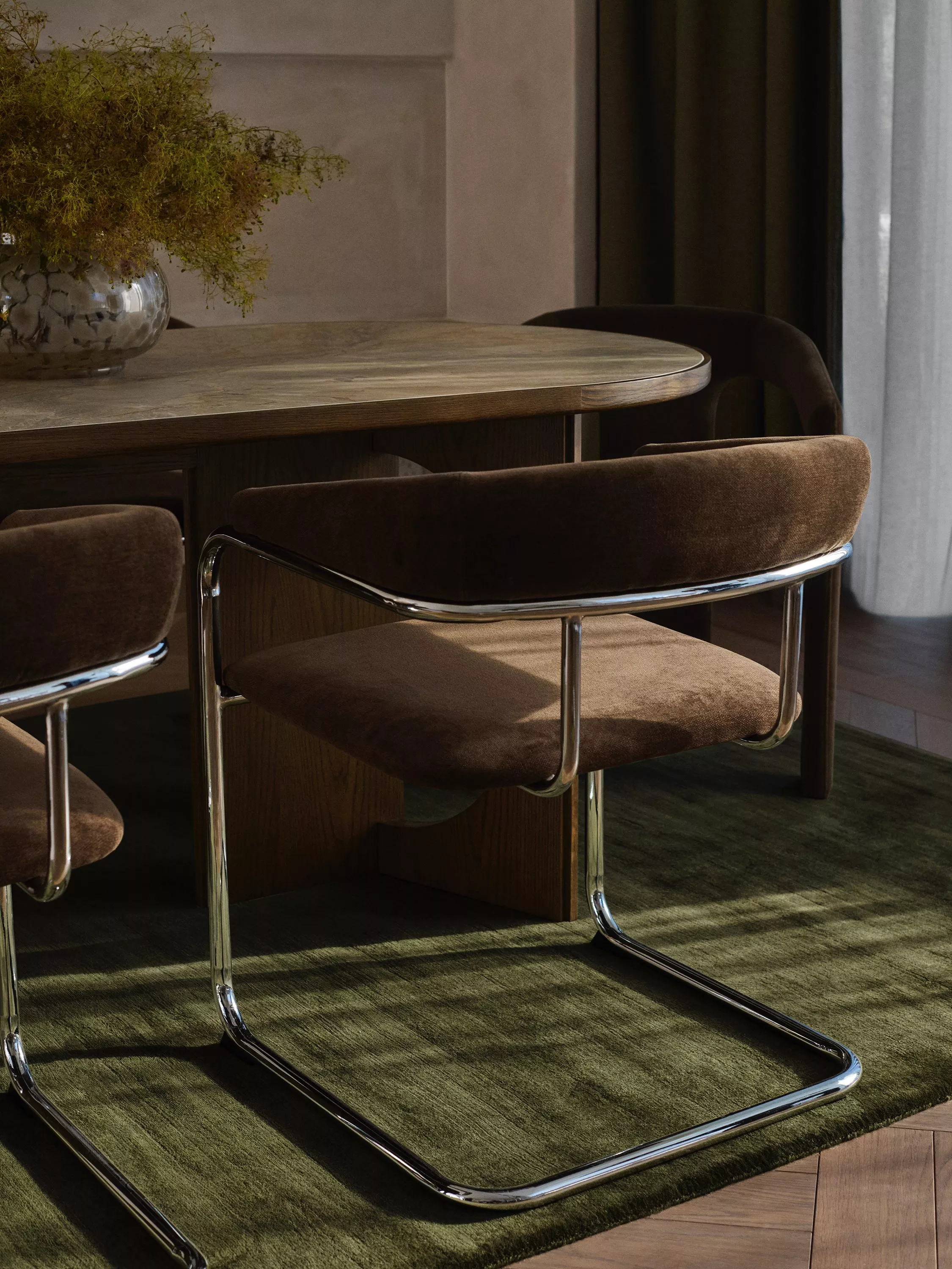 Dining table with curved brown velvet dining chairs and the table laid in an elaborate way this candles and foliage