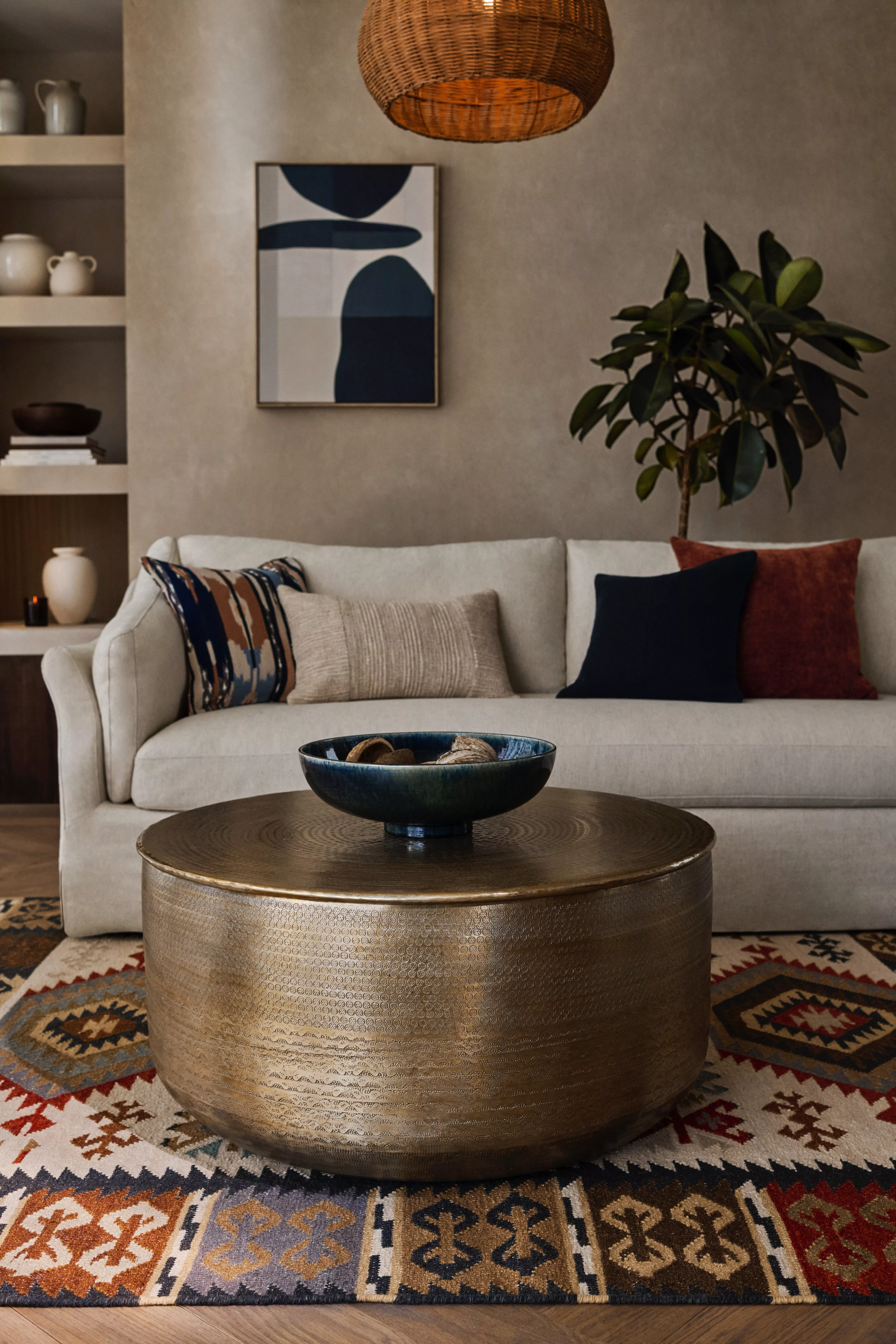 Cream sofa with multi coloured cushions on a patterned rug with a brass coffee table 