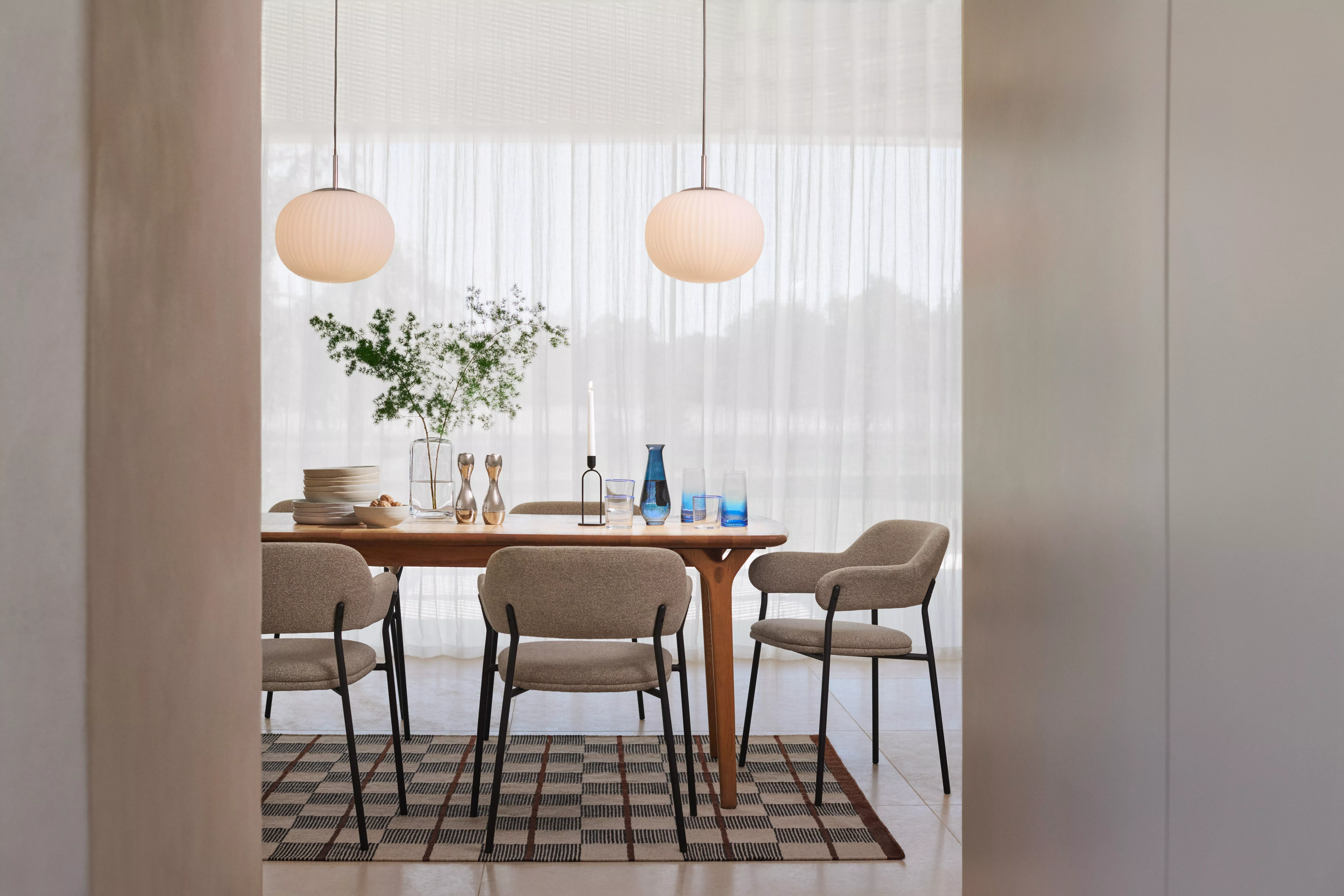 Scandi dining table with chairs and table made up with a vase, plates, glasses and a candle