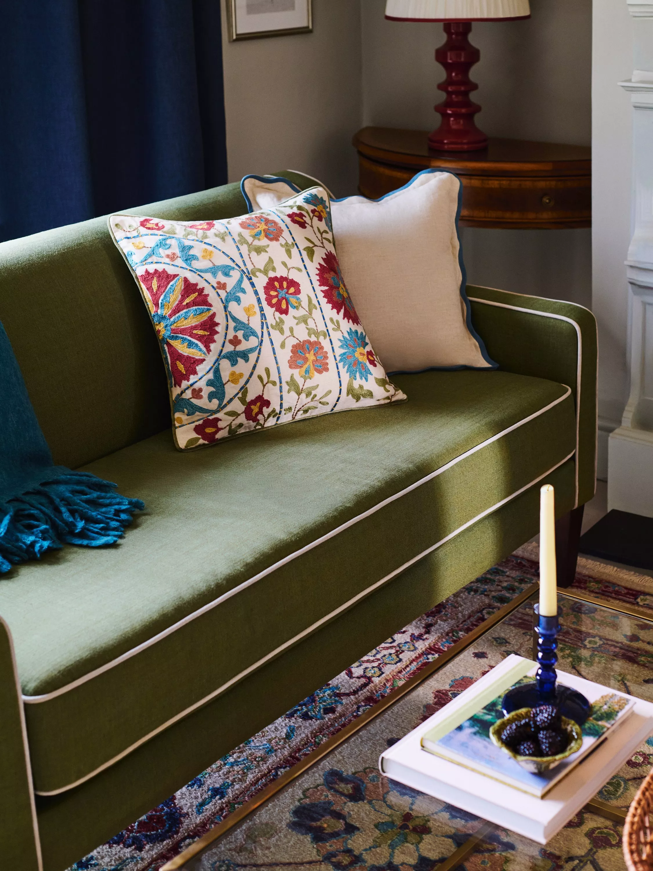 Green sofa with white trim and colourful cushion 
