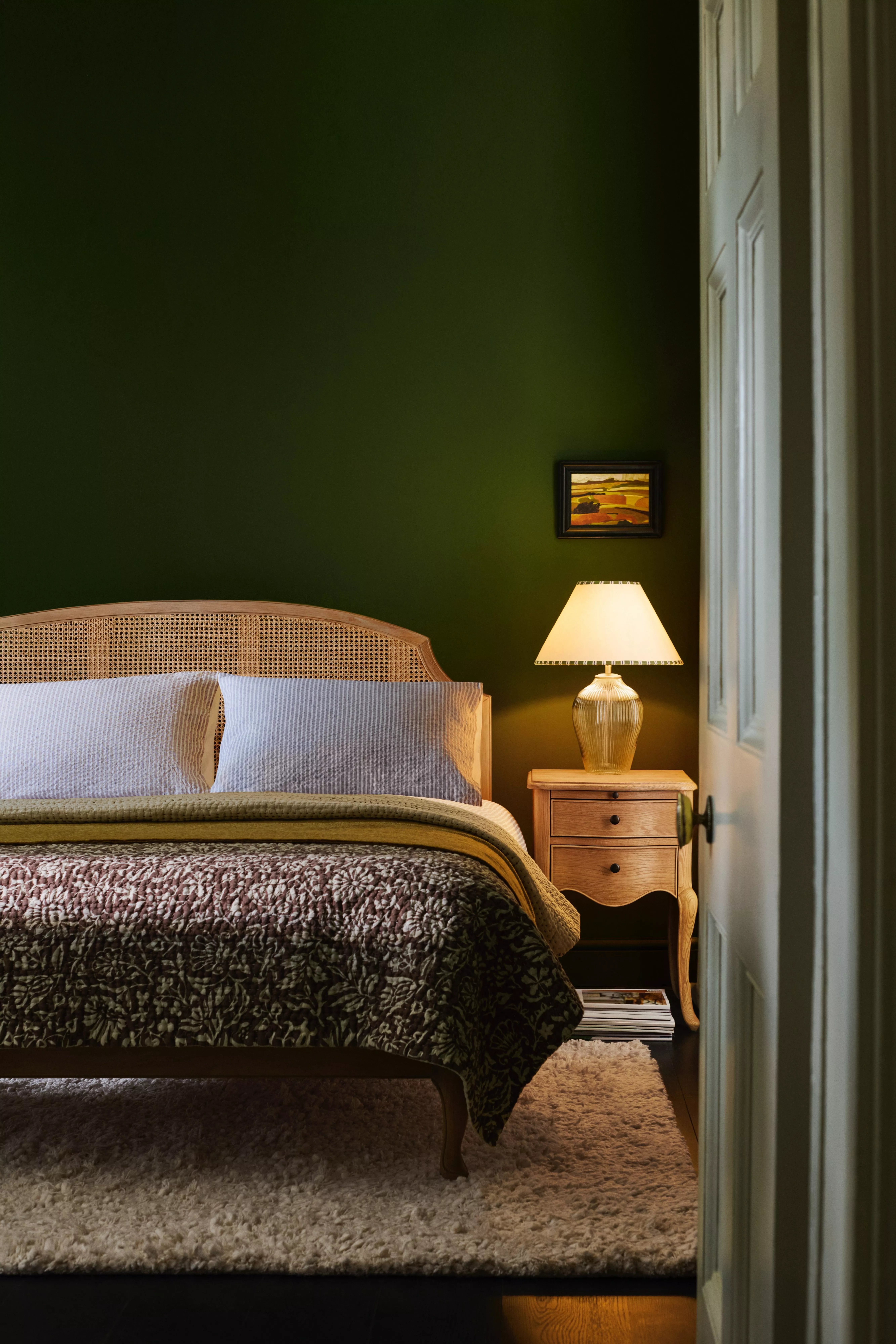 A bed with pink and green pillows and a green duvet