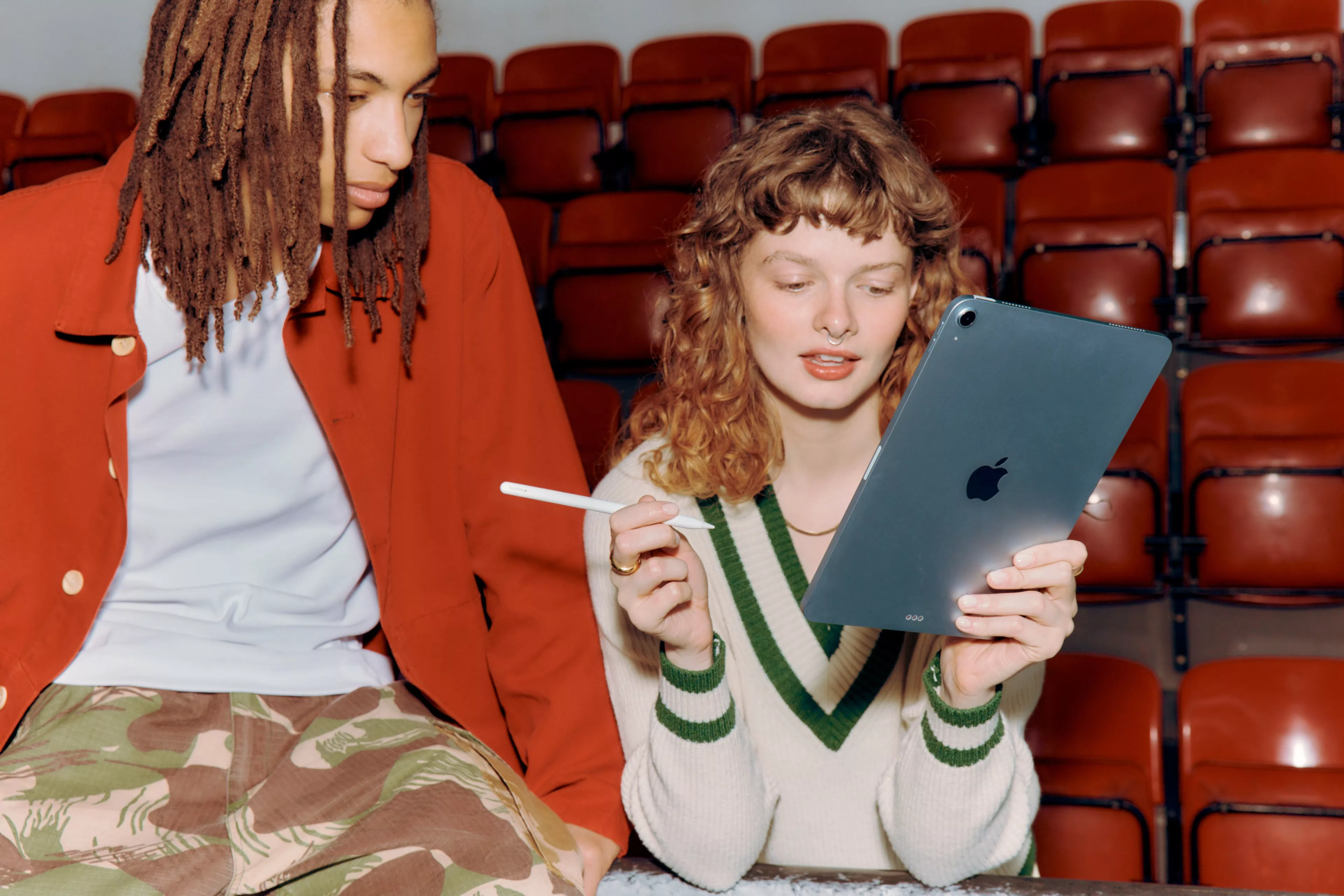 girl with ipad in left hand and apple pen in the other hand. person looking at the ipad