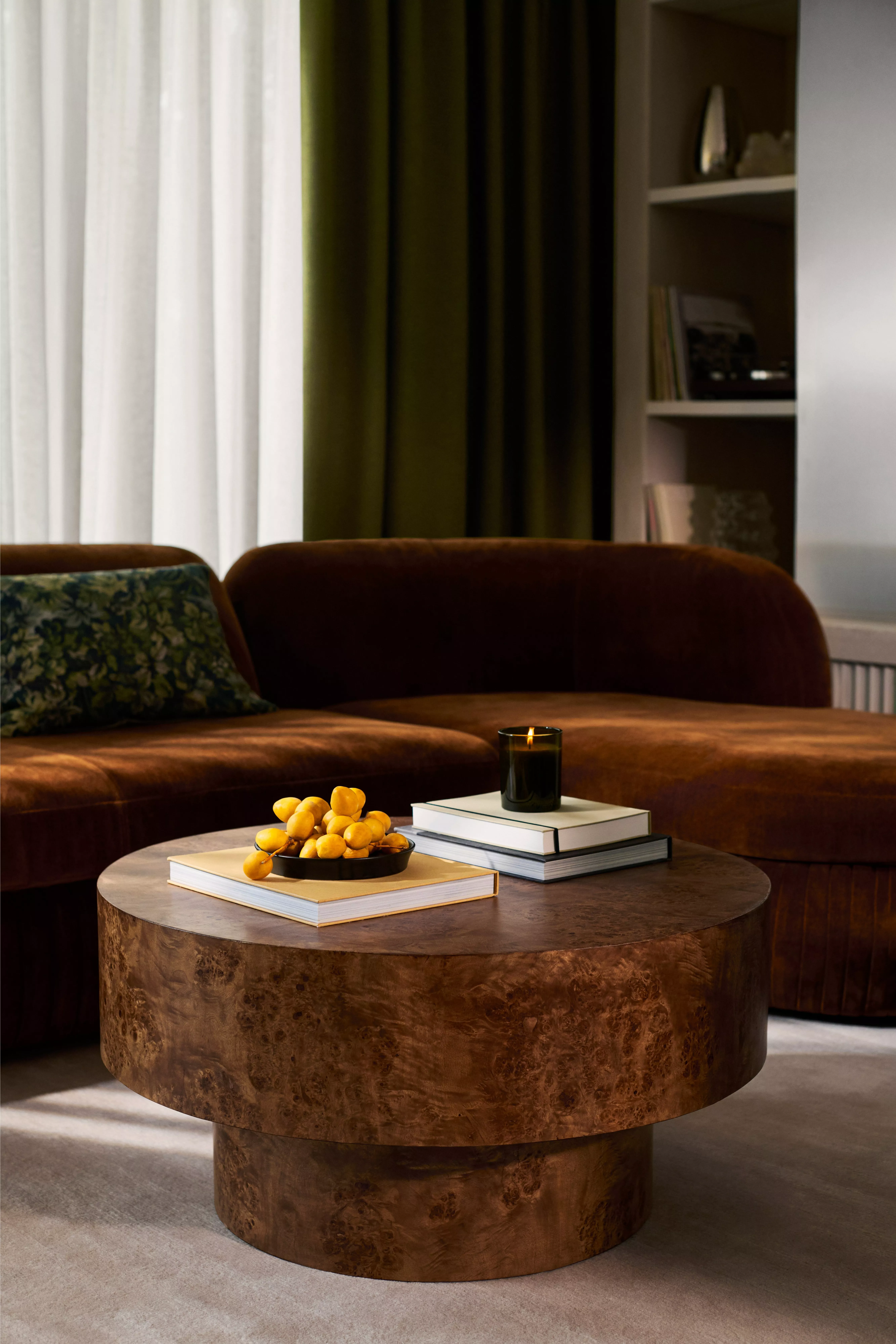  A burl wood round coffee table with books and a candle on top